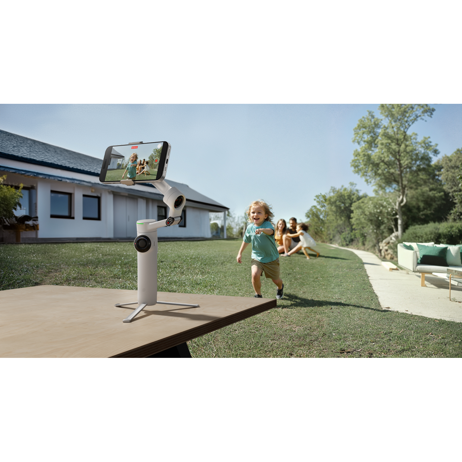 A child running in a yard, a phone on a selfie stick filming them.