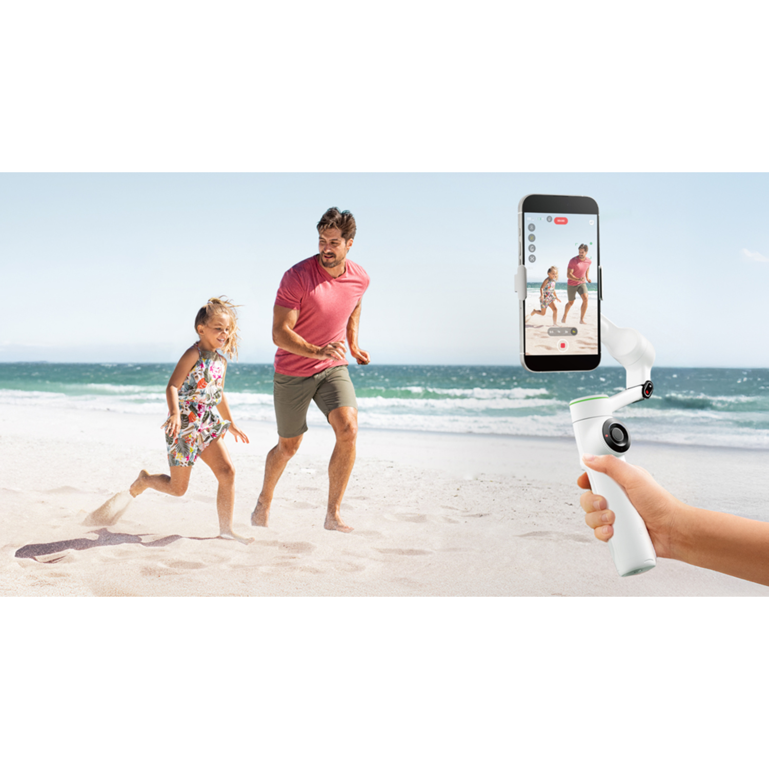 A man and child running on the beach with a phone recording them.