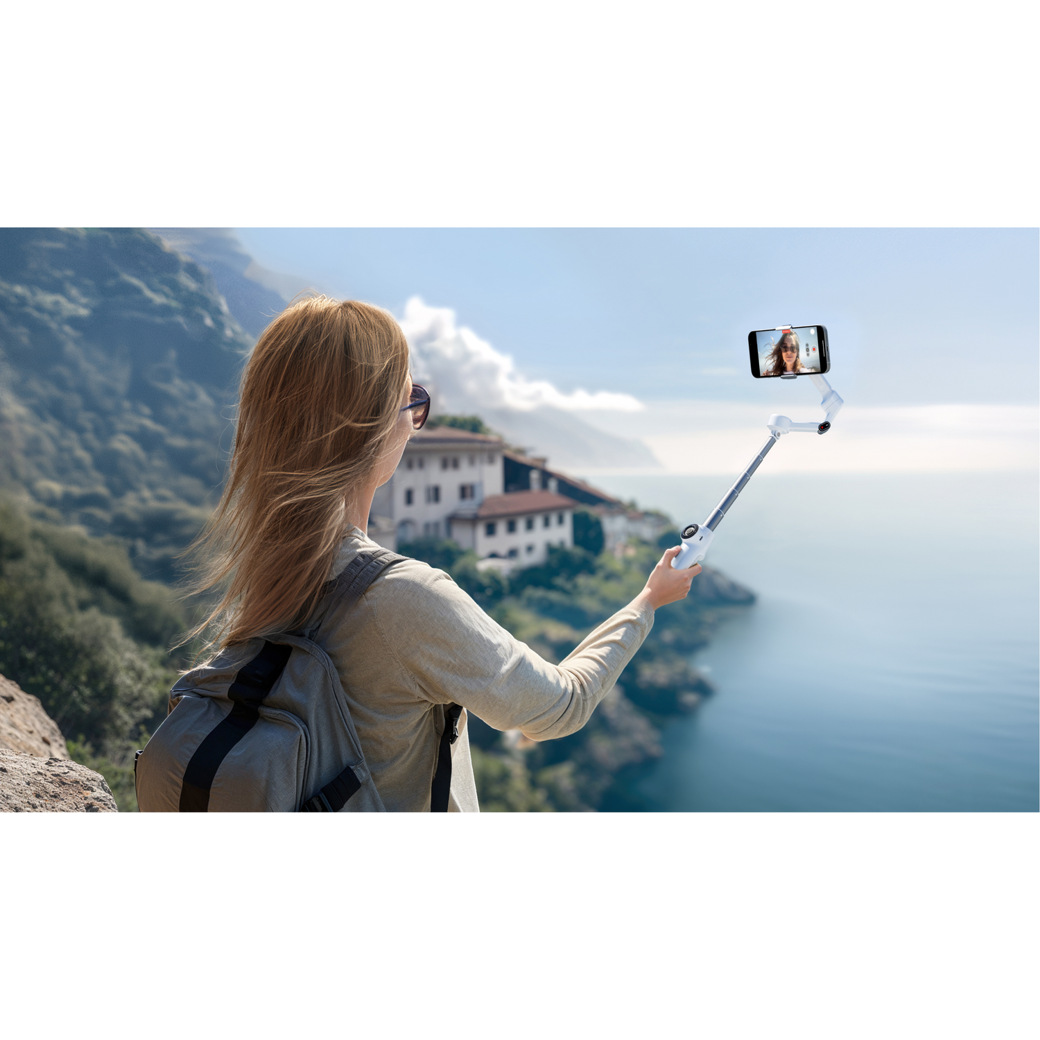 Woman taking a selfie with a selfie stick near the sea.