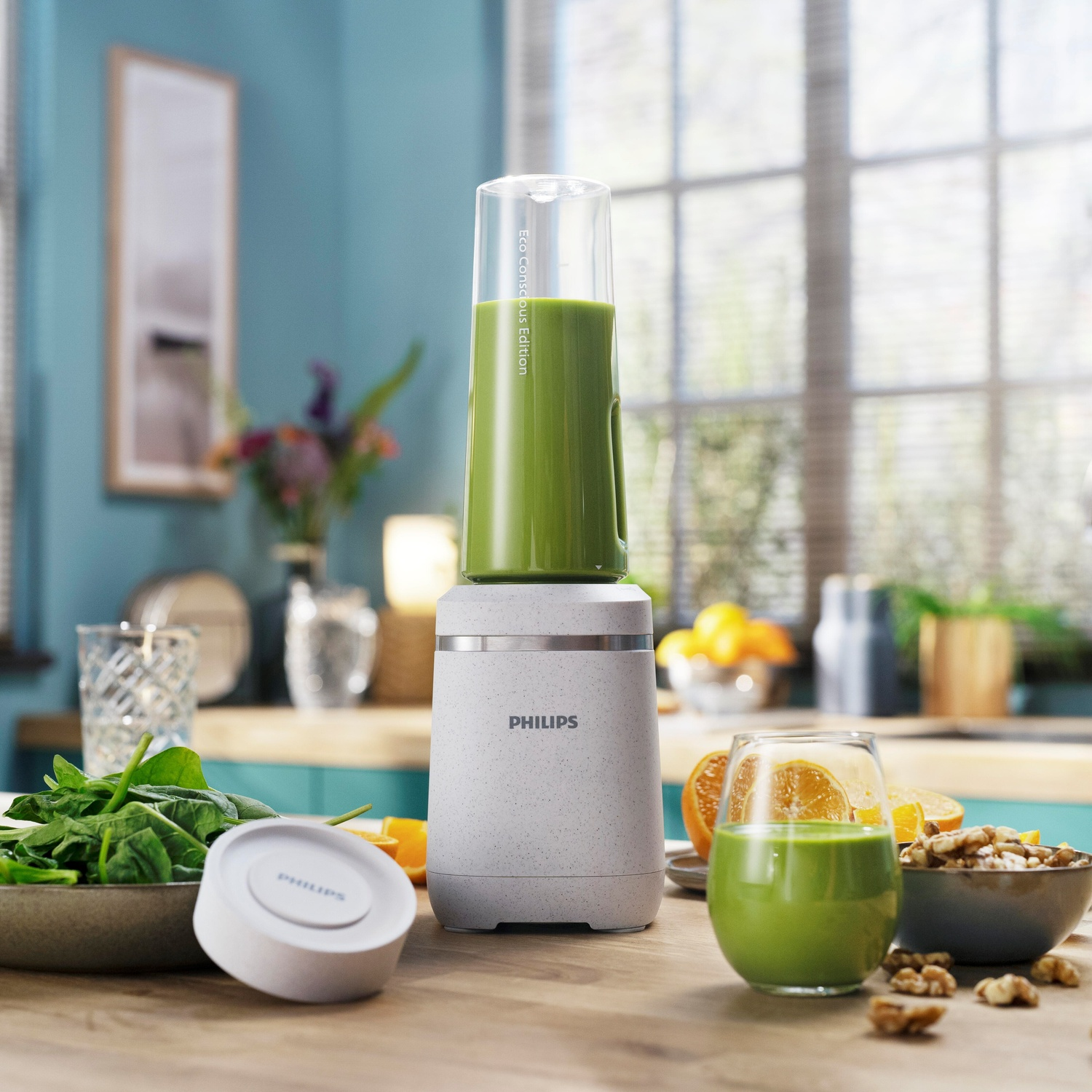 Un frullatore con un frullato verde, circondato da ingredienti come spinaci e arance.