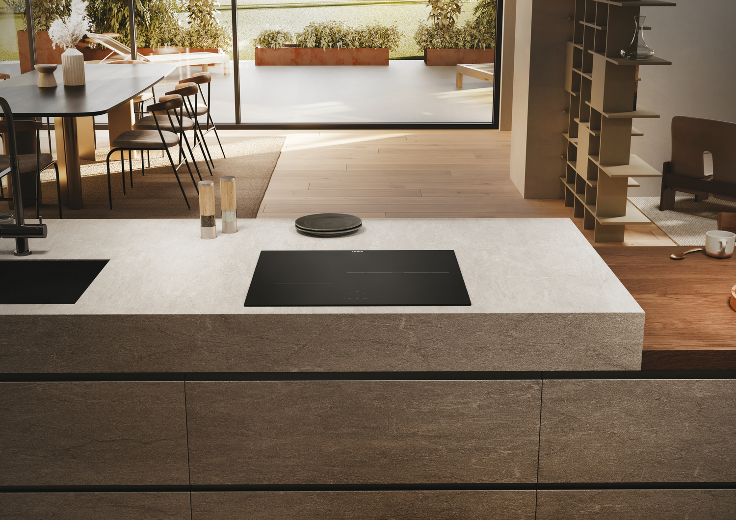 Una isla de cocina moderna con una placa de inducción negra y varios elementos de cocina.
