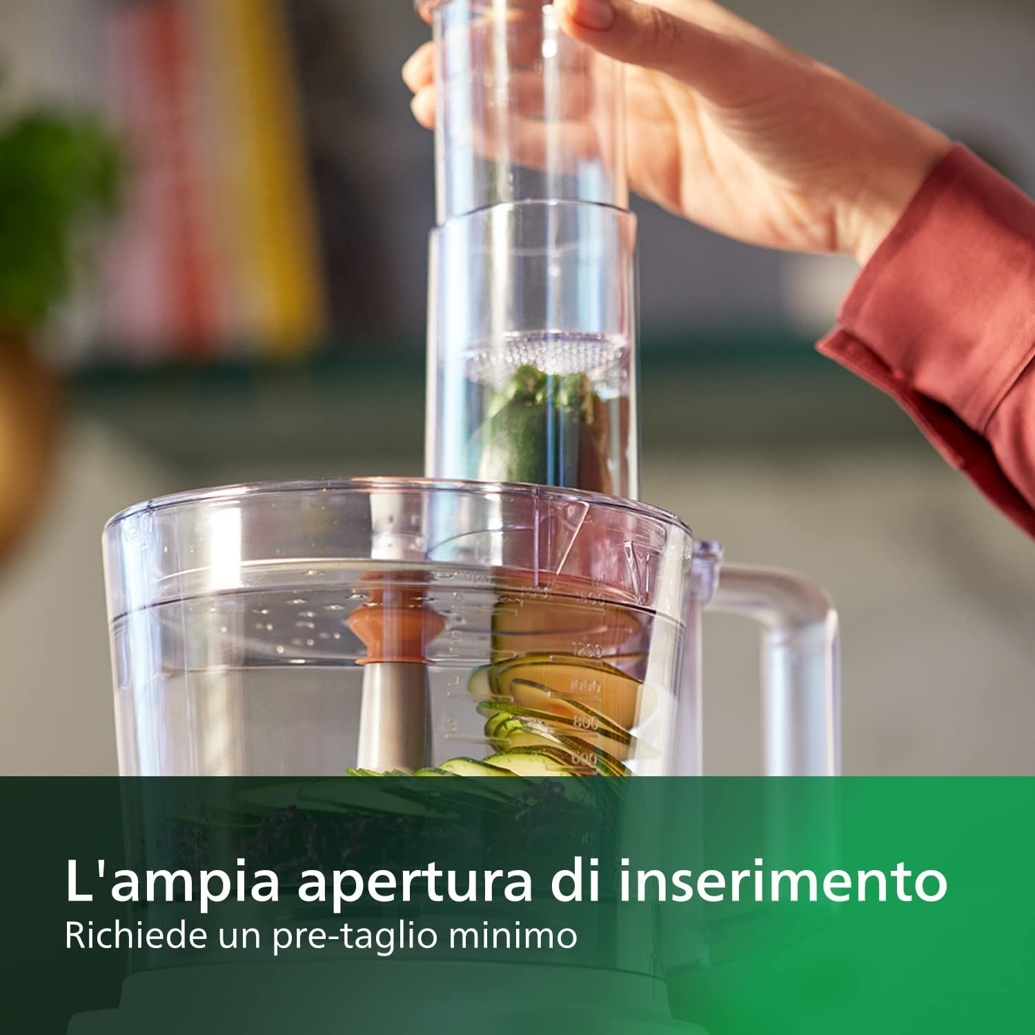 Una mano che inserisce ingredienti in un robot da cucina.