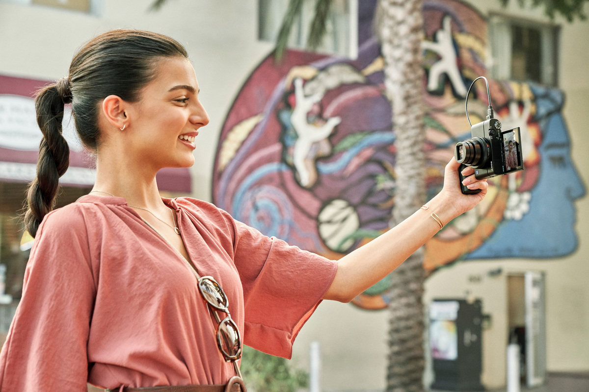 Donna che fa un selfie con una fotocamera. Sfondo murale colorato.