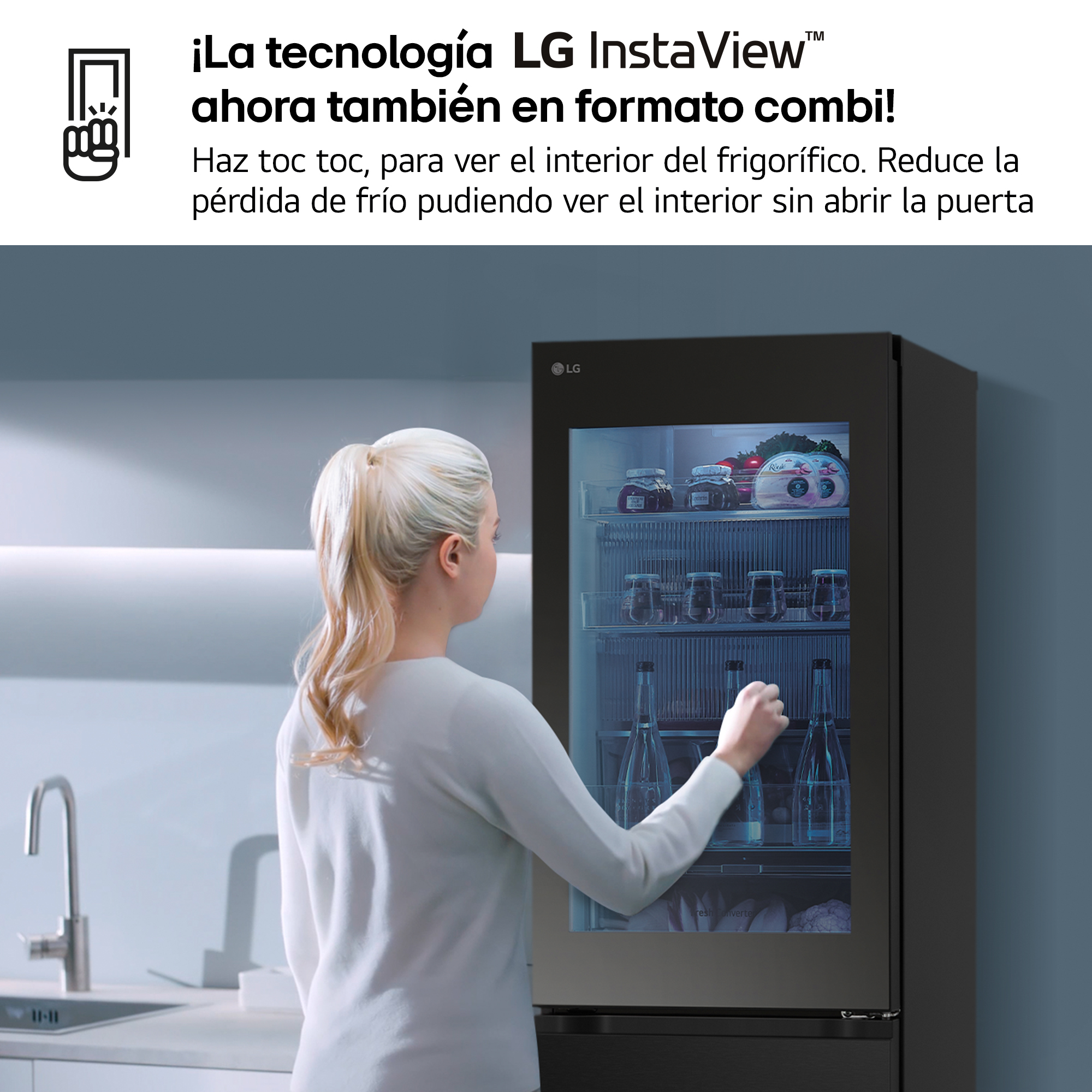 Mujer mirando una nevera con puerta de cristal. La nevera es negra. La cocina está al fondo.