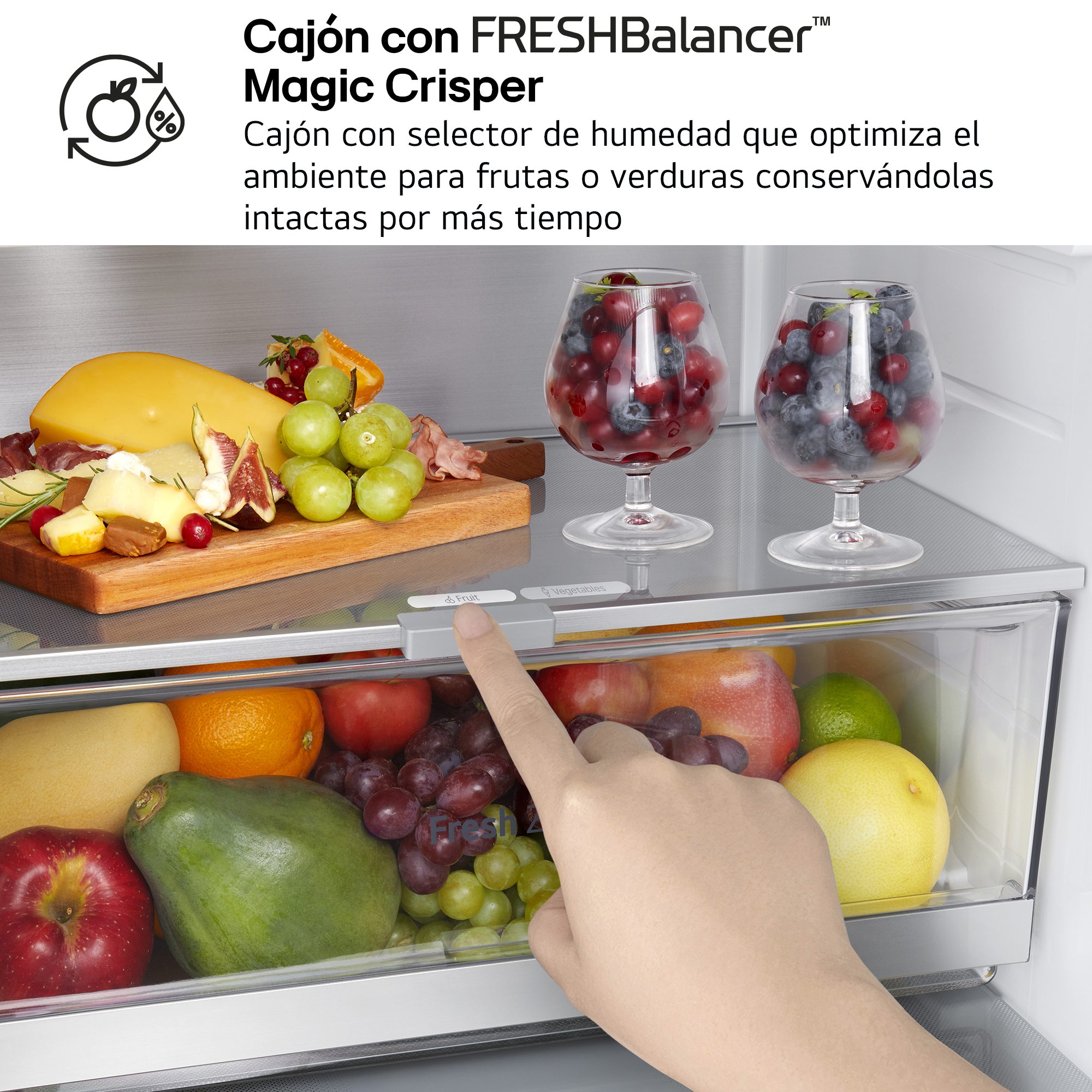 Un cajón de refrigerador con frutas y verduras frescas. Una mano toca el control de humedad.