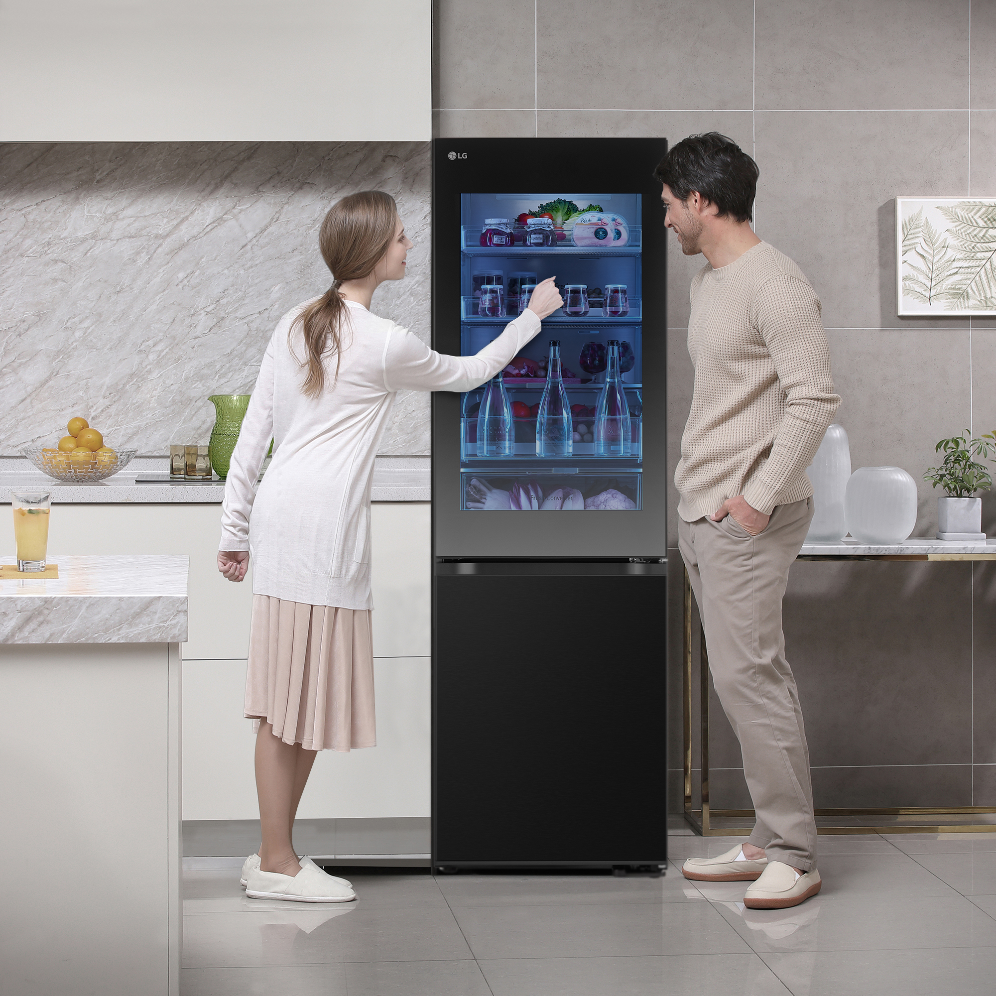Una pareja mirando el contenido de un refrigerador negro.