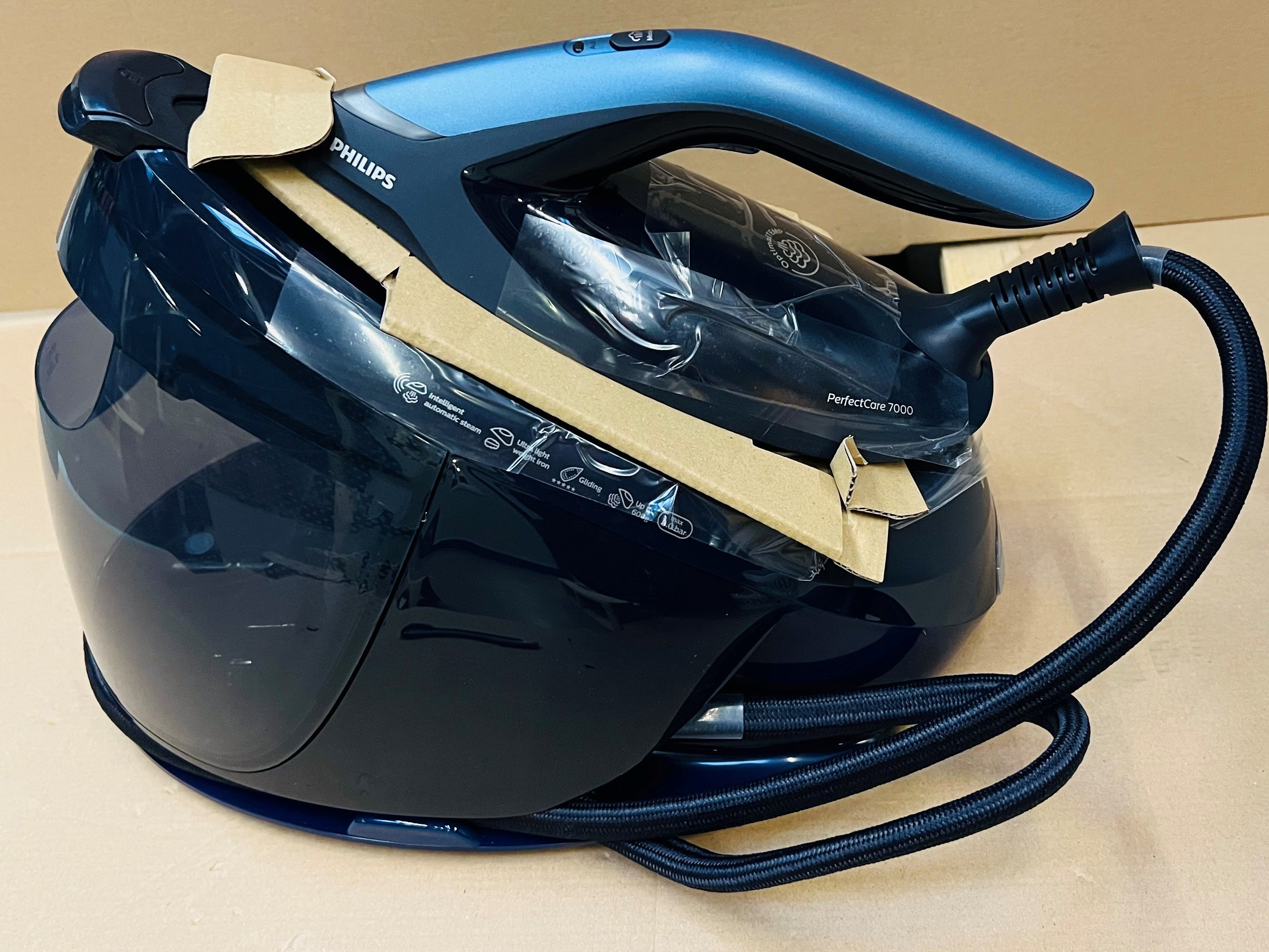Żelazko parowe Philips PerfectCare 7000, niebiesko-czarne. Leży na kartonowej powierzchni.