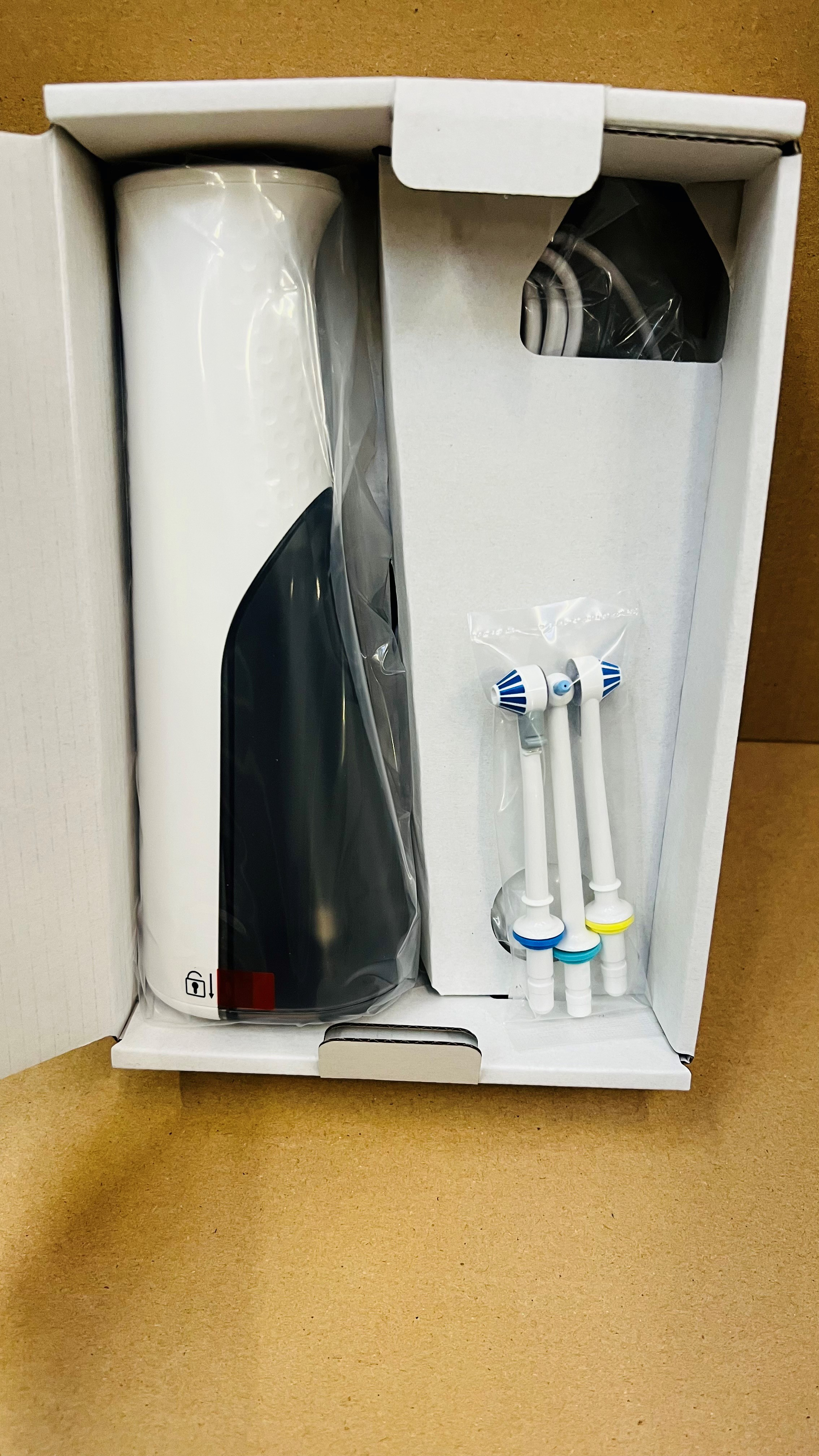 Biało-czarny irygator wodny z trzema końcówkami w pudełku.