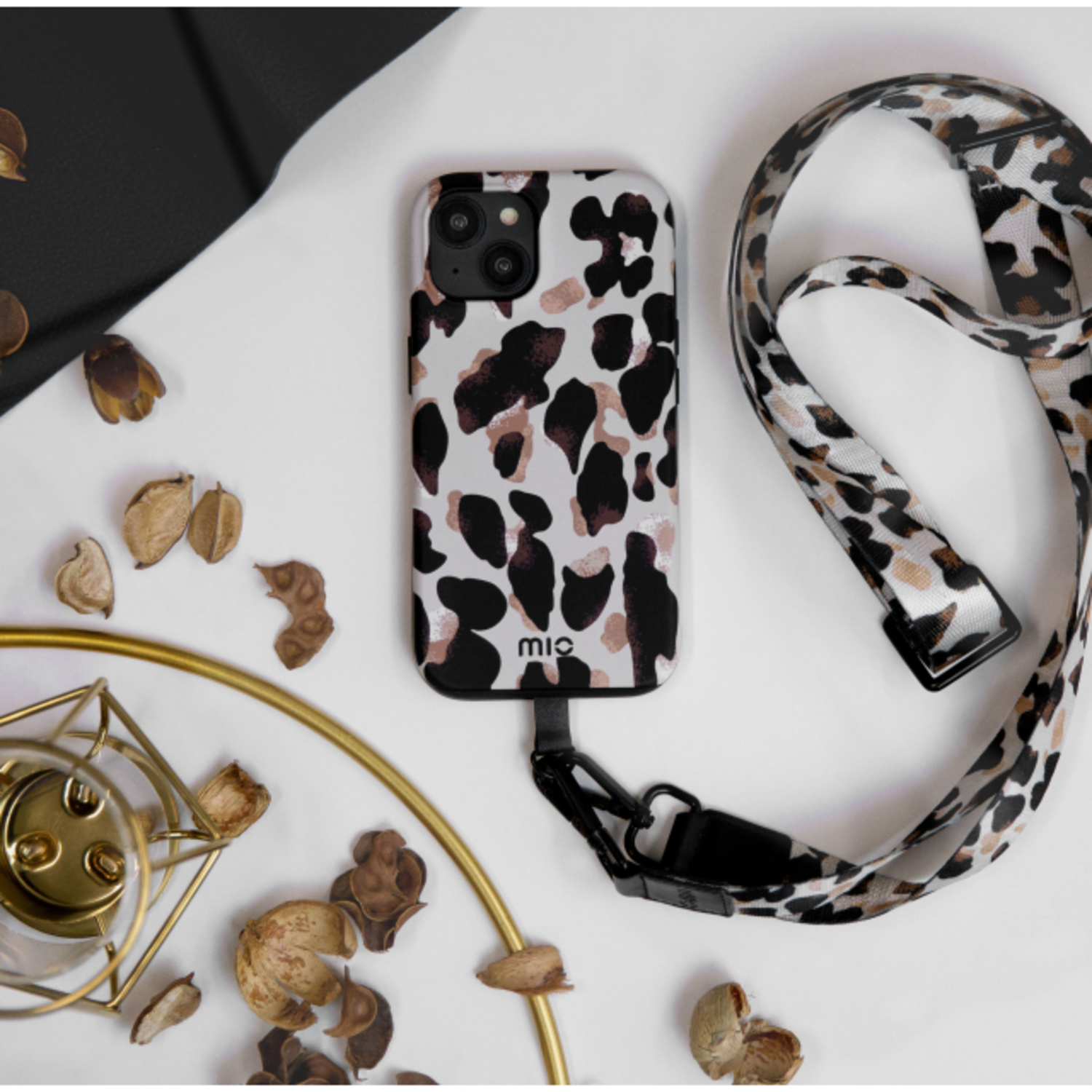Phone case with a leopard pattern, connected to a matching lanyard, on a white surface.