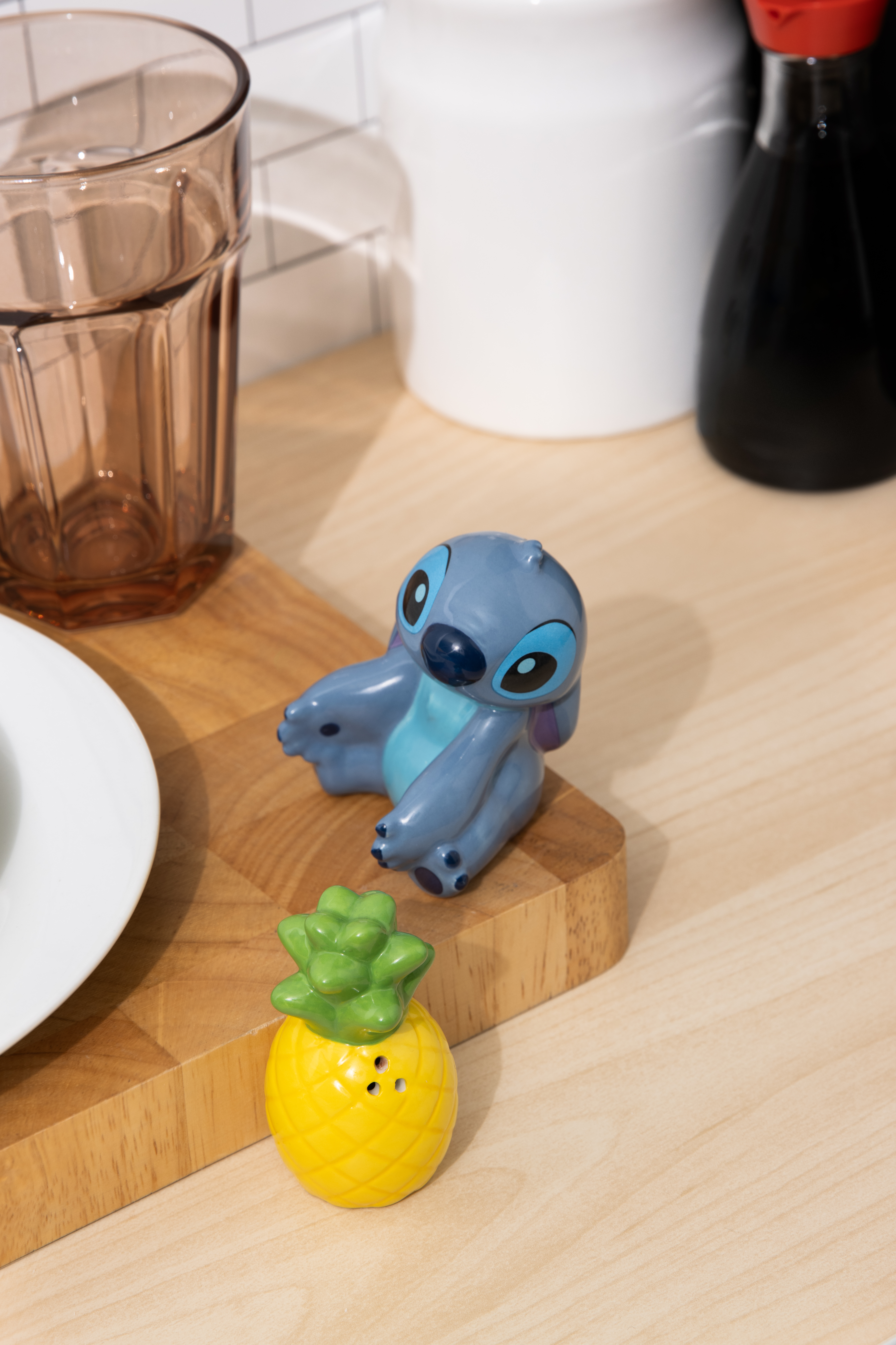 Stitch- und Ananassalz- und Pfefferstreuer auf einem Holzbrett. Küchenhintergrund.