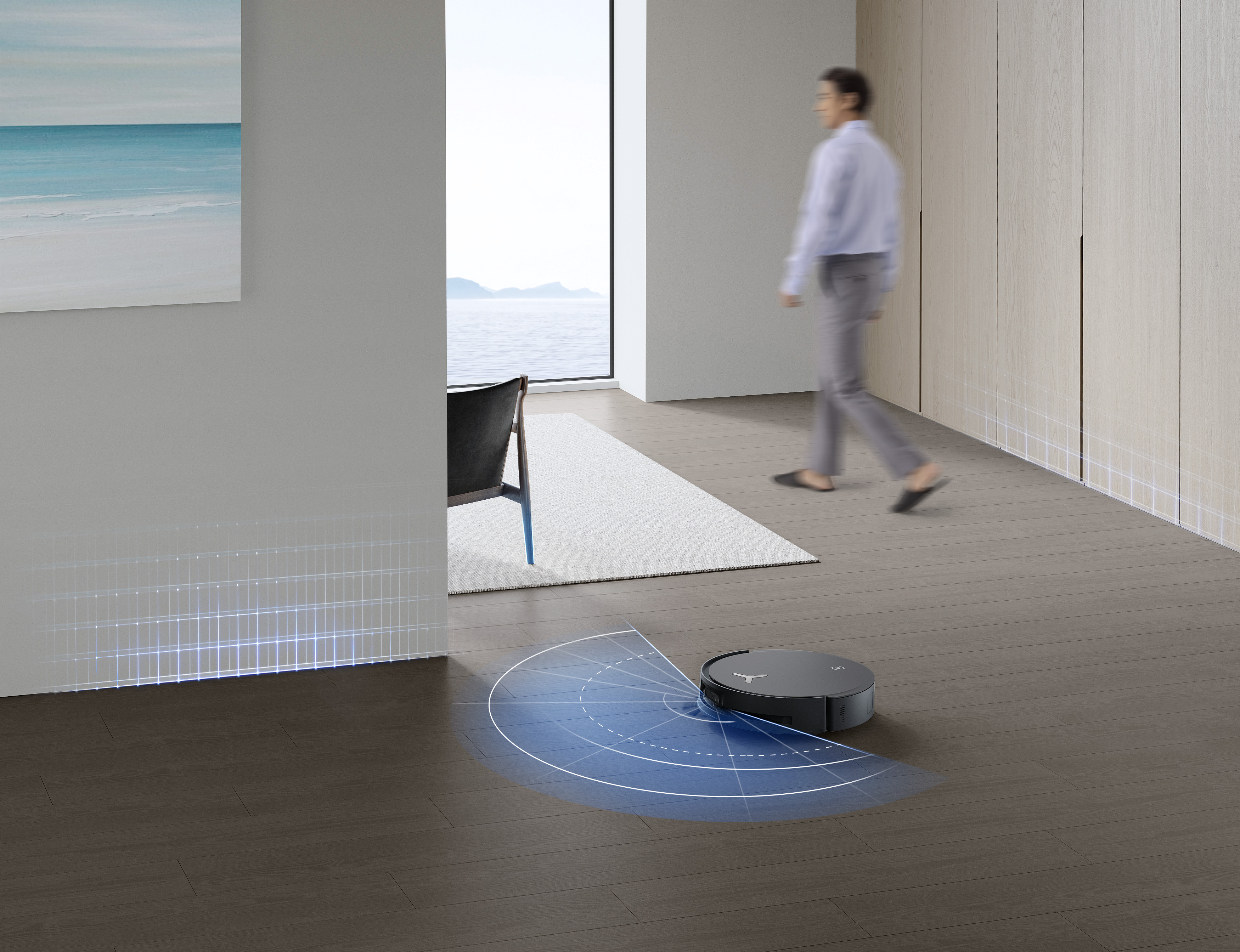 Roboter-Staubsauger auf Holzboden, mit einer Person im Hintergrund.