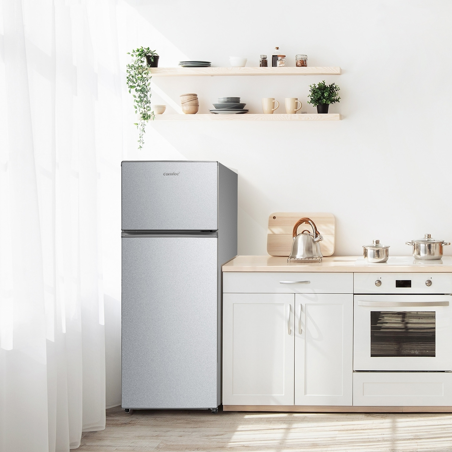 Frigorifero argentato in una cucina. La cucina ha mobili bianchi, mensole in legno e una finestra.
