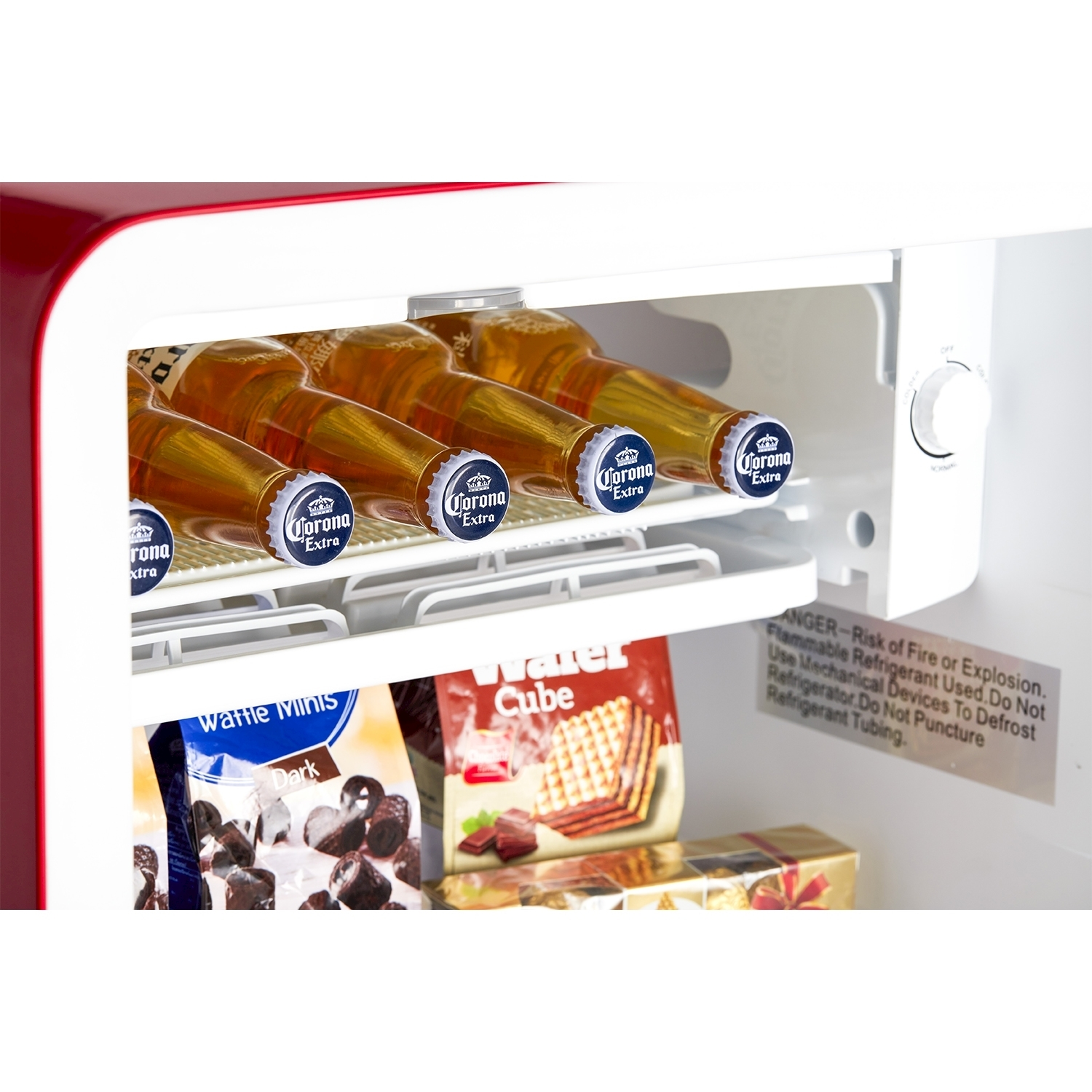 Interno di un mini-frigo con bottiglie di birra, snack e un quadrante della temperatura.