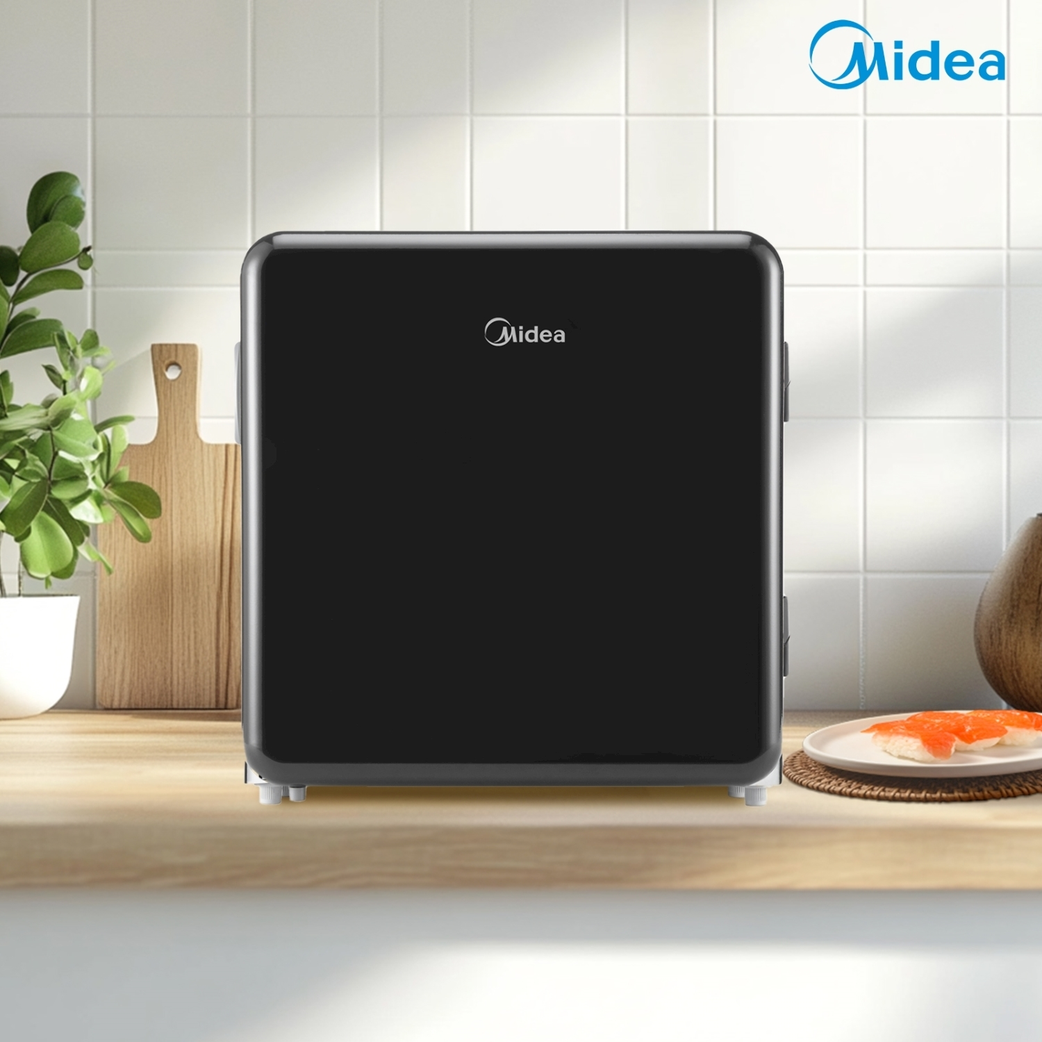Un mini-frigo nero su un piano di lavoro in legno. Sono visibili uno sfondo di piastrelle bianche e il logo Midea.