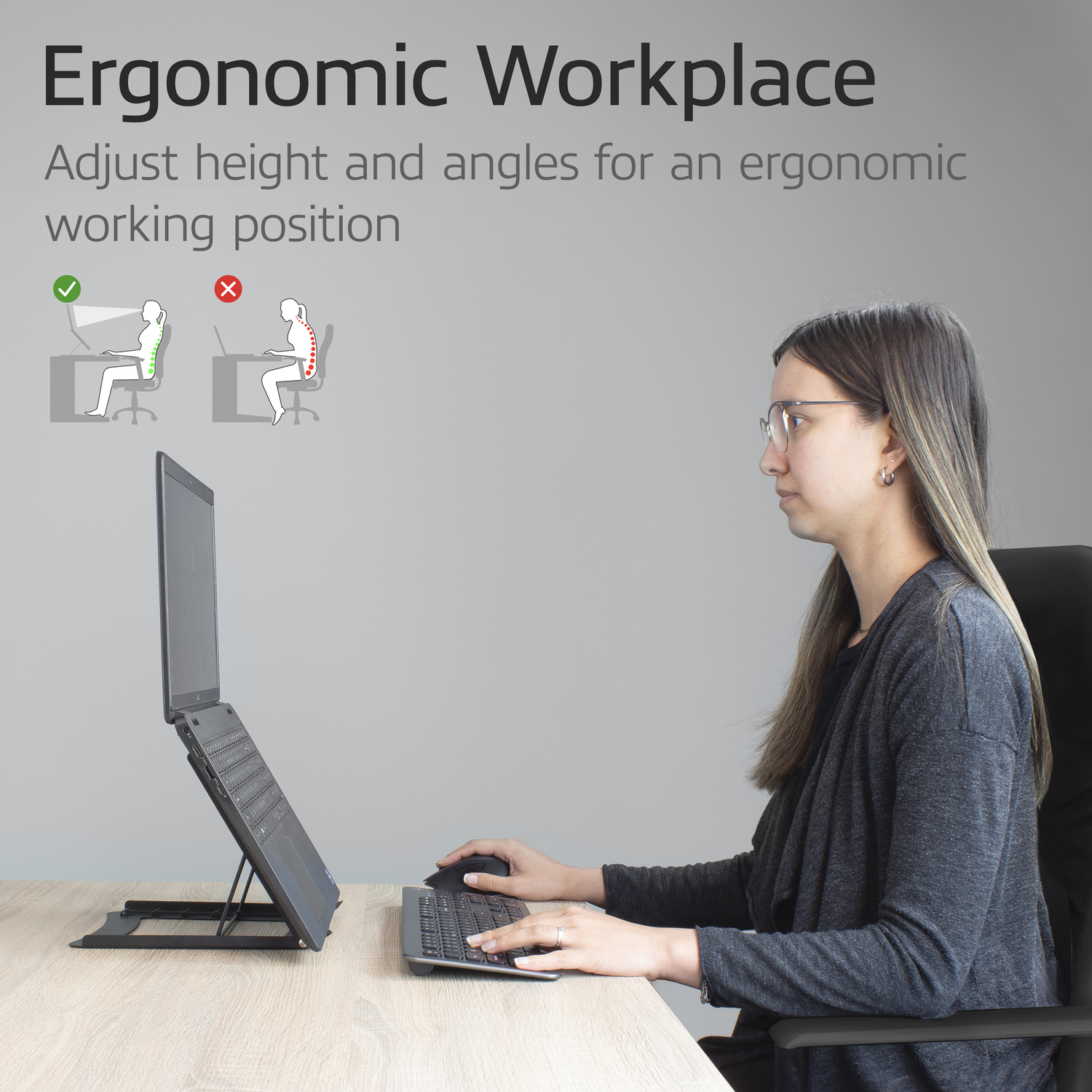 Woman using laptop on a stand, demonstrating ergonomic workplace setup.  Grey background.