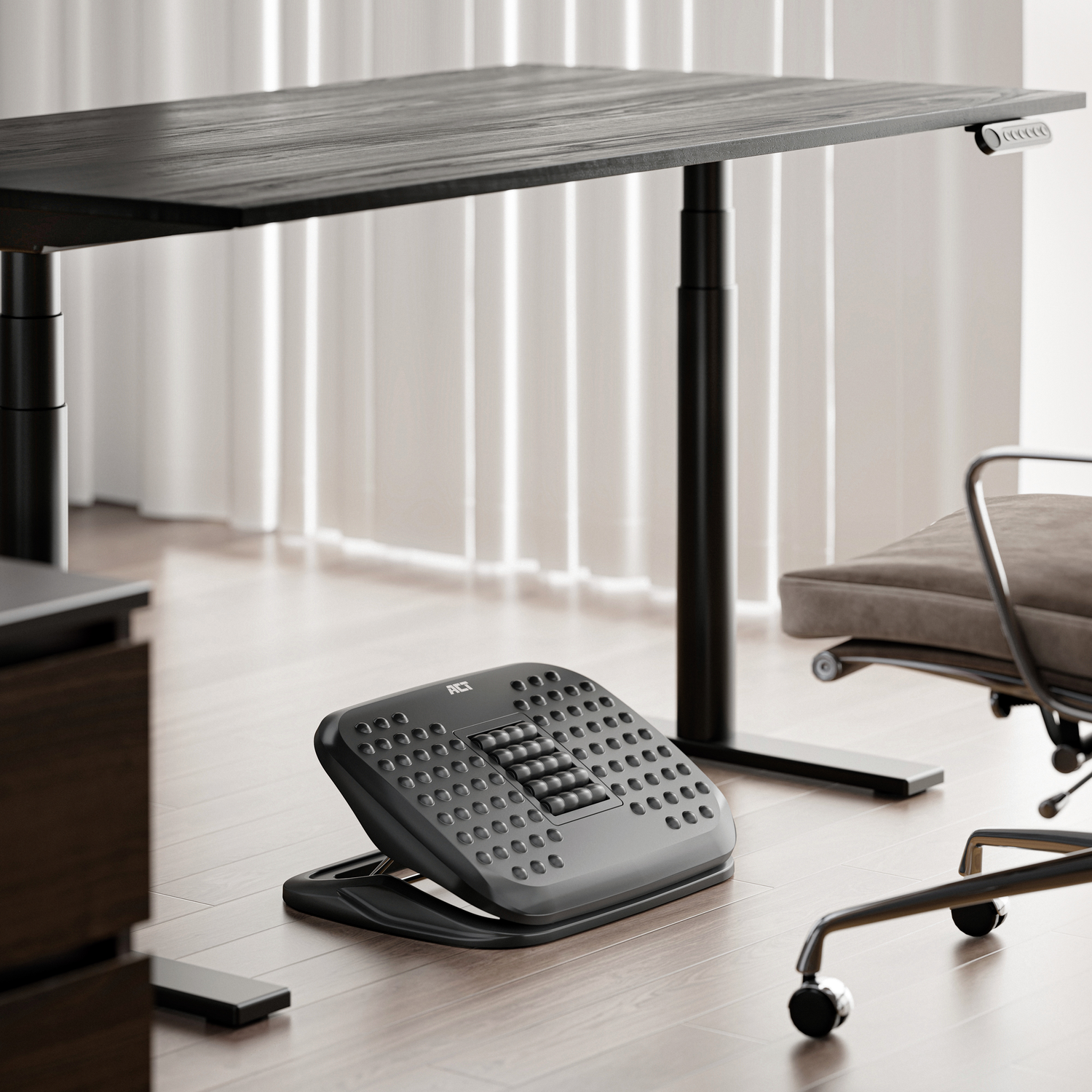 A black footrest on the floor under a desk and a chair.