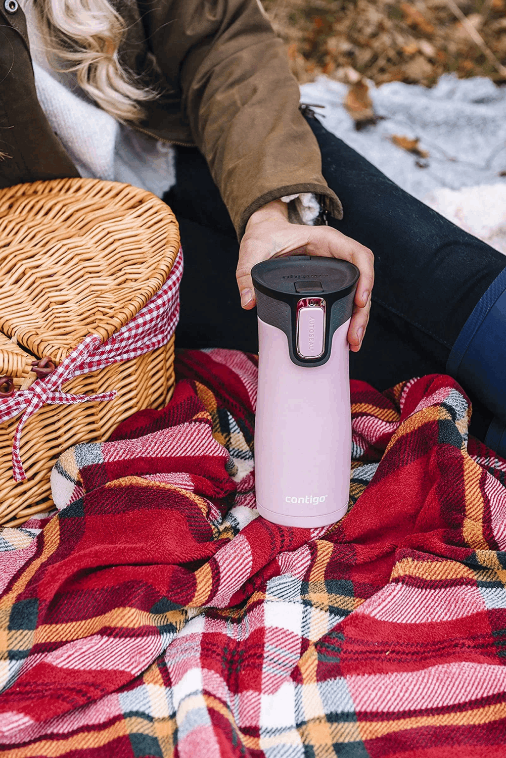 Una escena de picnic con un termo rosa y una manta a cuadros. Una cesta es visible.