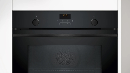 Un horno negro con pantalla digital y perillas, sobre fondo de pared blanca.