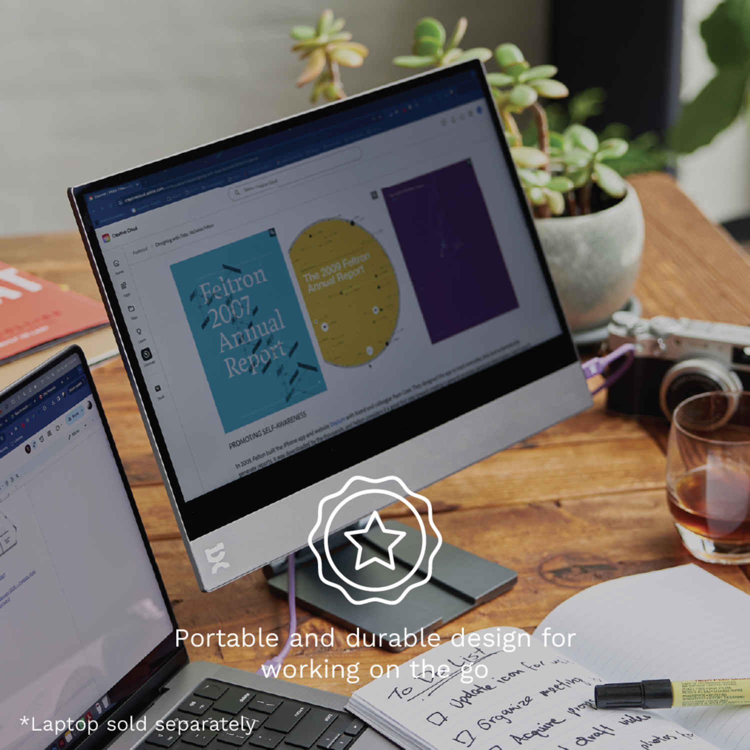A laptop with a display, a glass of liquid, a pen, and a notebook on a wooden table.