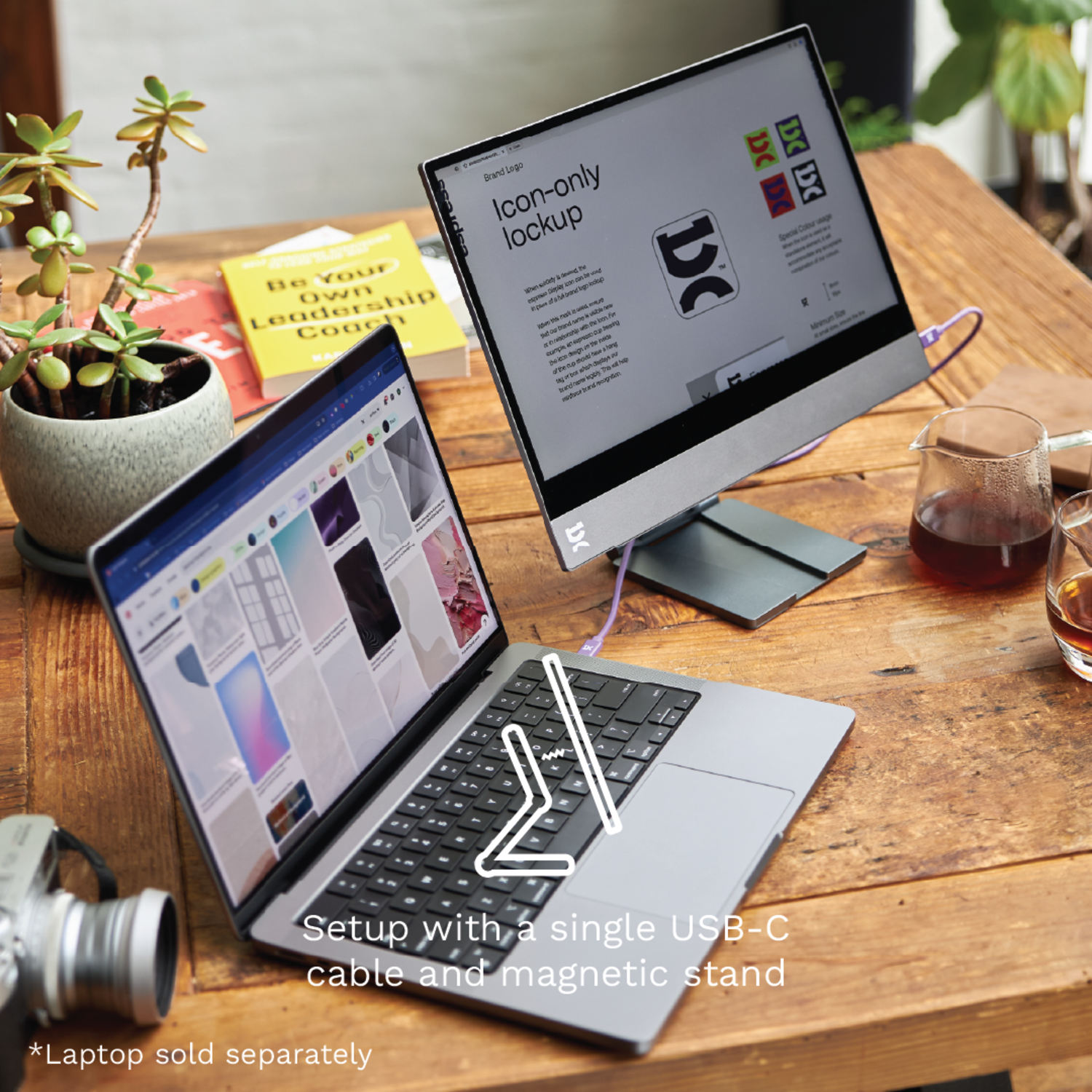 Laptop with an interactive touchscreen monitor on a wooden desk. A plant and coffee cup.