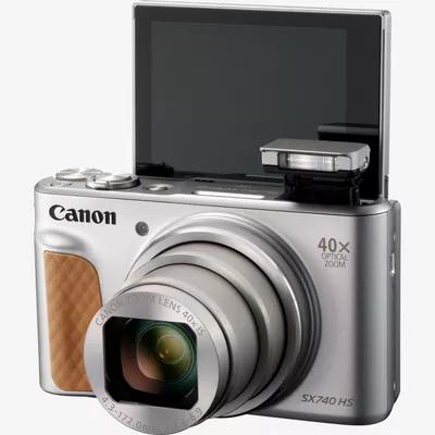 Silberne Canon-Kamera mit geöffnetem Bildschirm, Objektiv und Blitz, weißer Hintergrund.