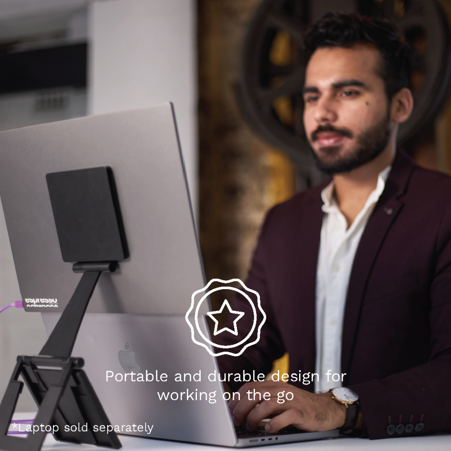 A man working on a laptop held by a black laptop stand.