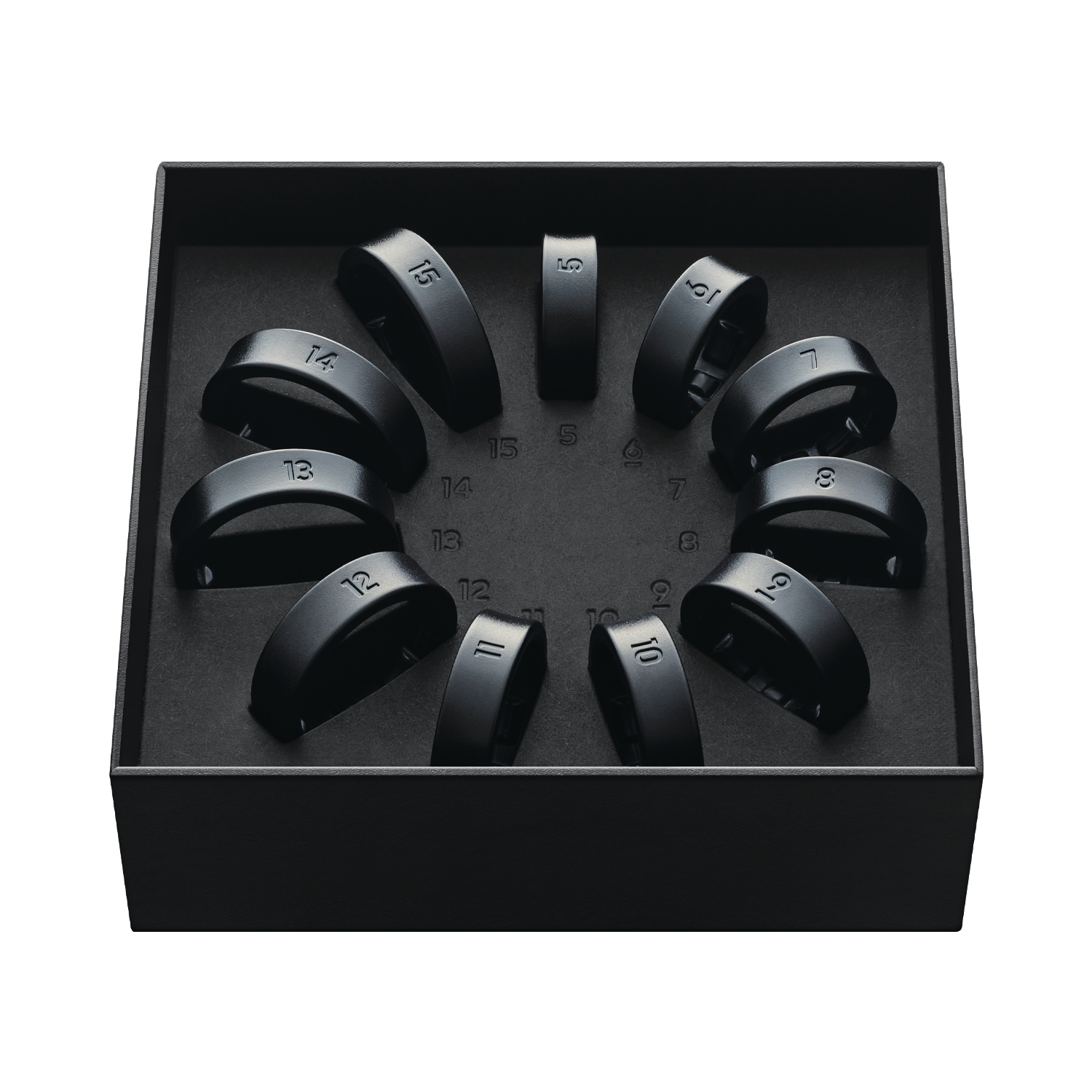 Geöffnete Schachtel mit schwarzen Ringen mit Zahlen. In einem Kreis angeordnet.