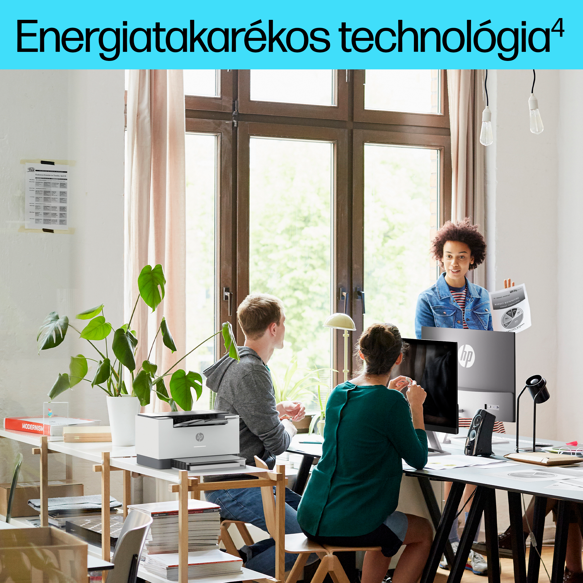 Irodai jelenet három emberrel. Két férfi és egy nő. Nyomtató, számítógép és egy növény az asztalon.
