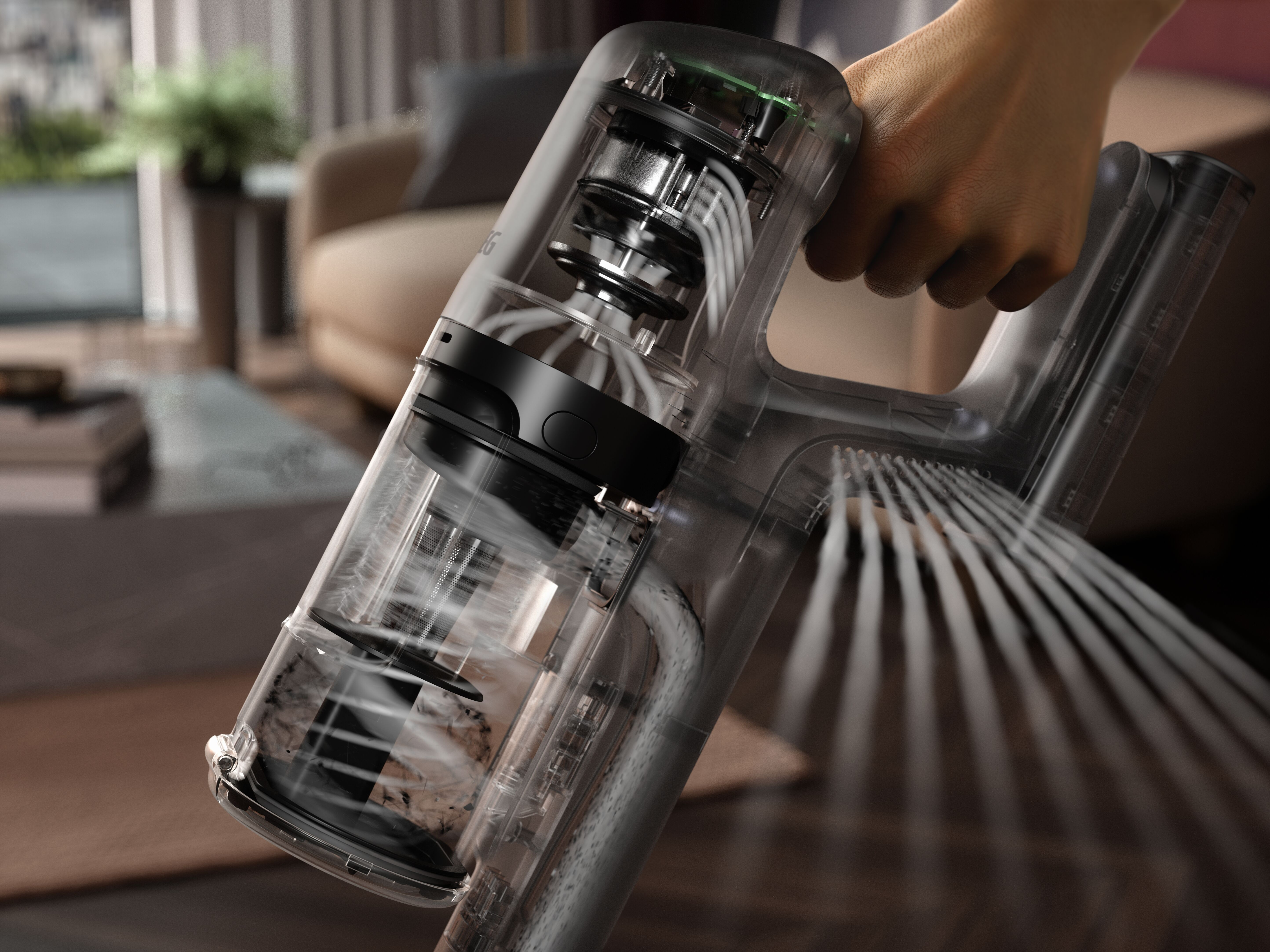 Transparenter Staubsauger, der die inneren Komponenten zeigt. Hand am Griff, verschwommenes Zuhause.
