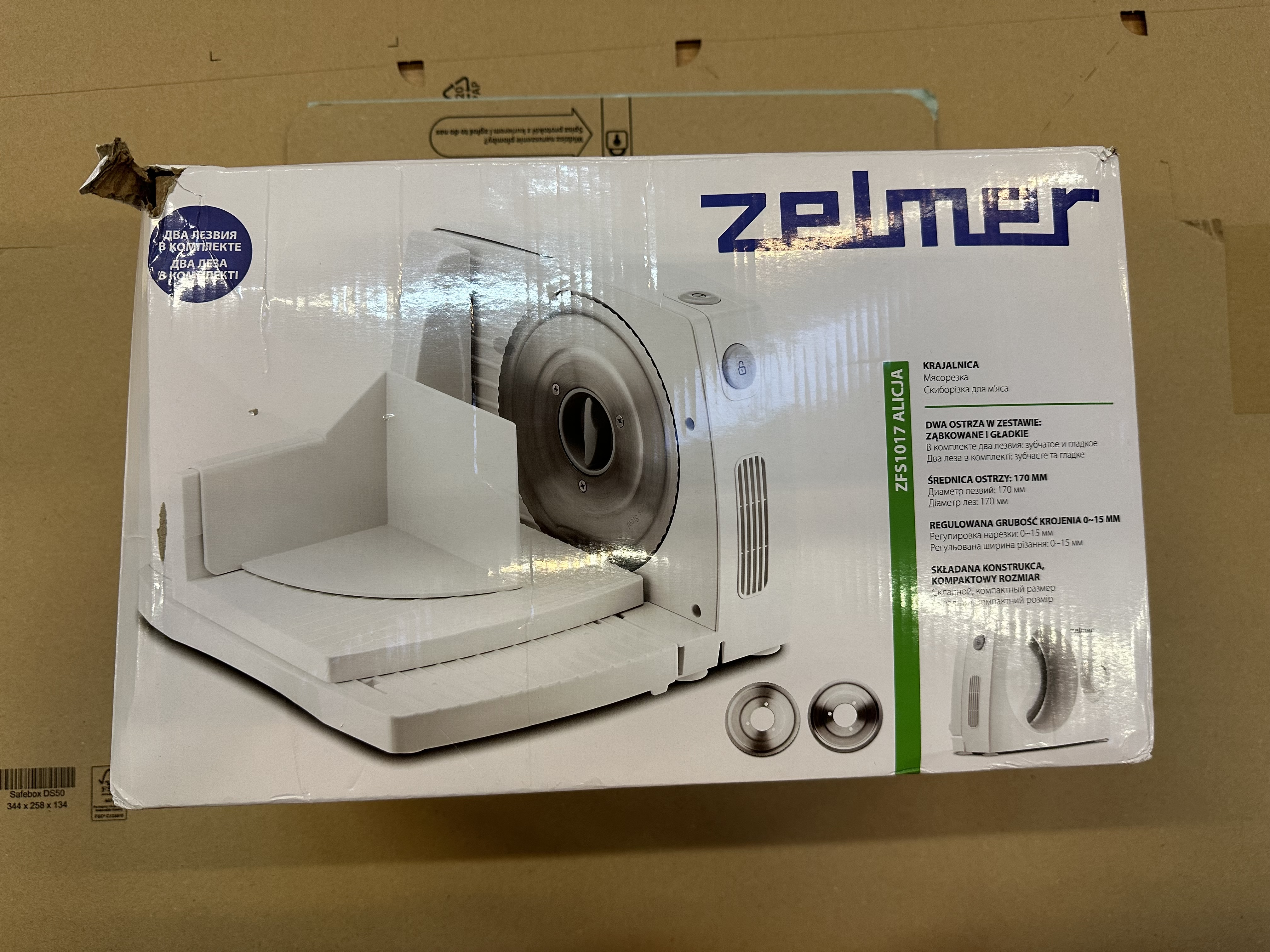 Pudełko krajalnicy do żywności Zelmer Alicia na kartonowej powierzchni.