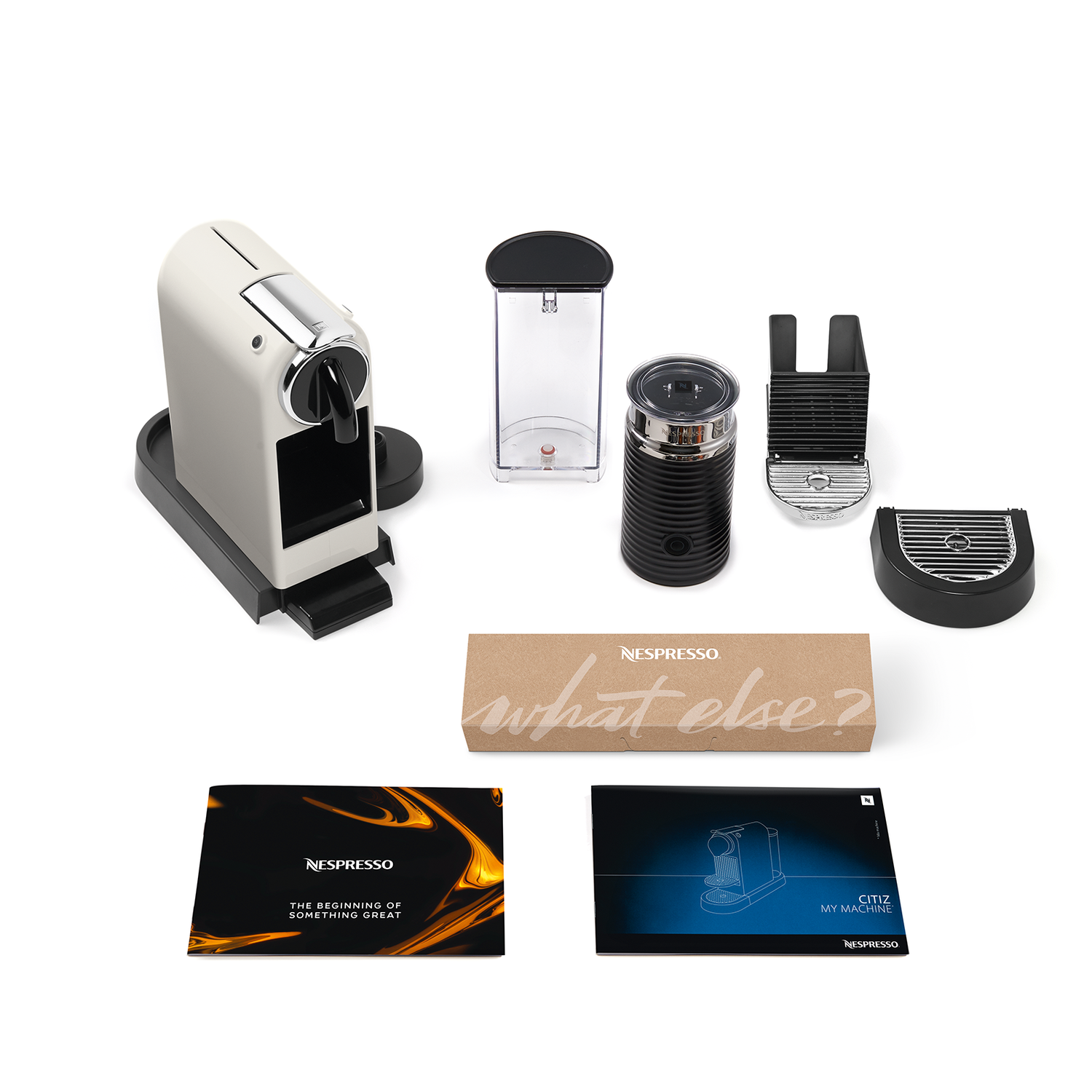 A Nespresso coffee machine with accessories, including milk frother, and manuals.