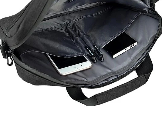 Otwarta torba na laptopa z telefonami i długopisami w środku. Czarny uchwyt i zamki błyskawiczne.