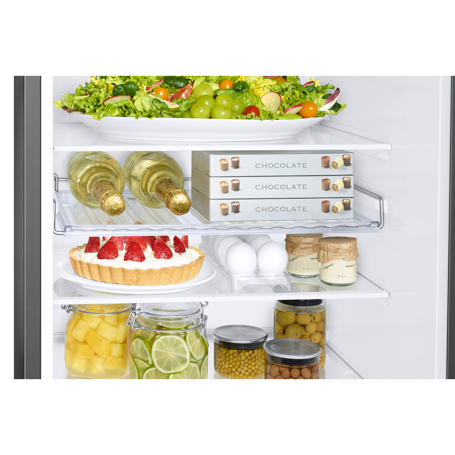 Interieur van koelkast met voedsel: salade, wijn, chocolade, eieren.