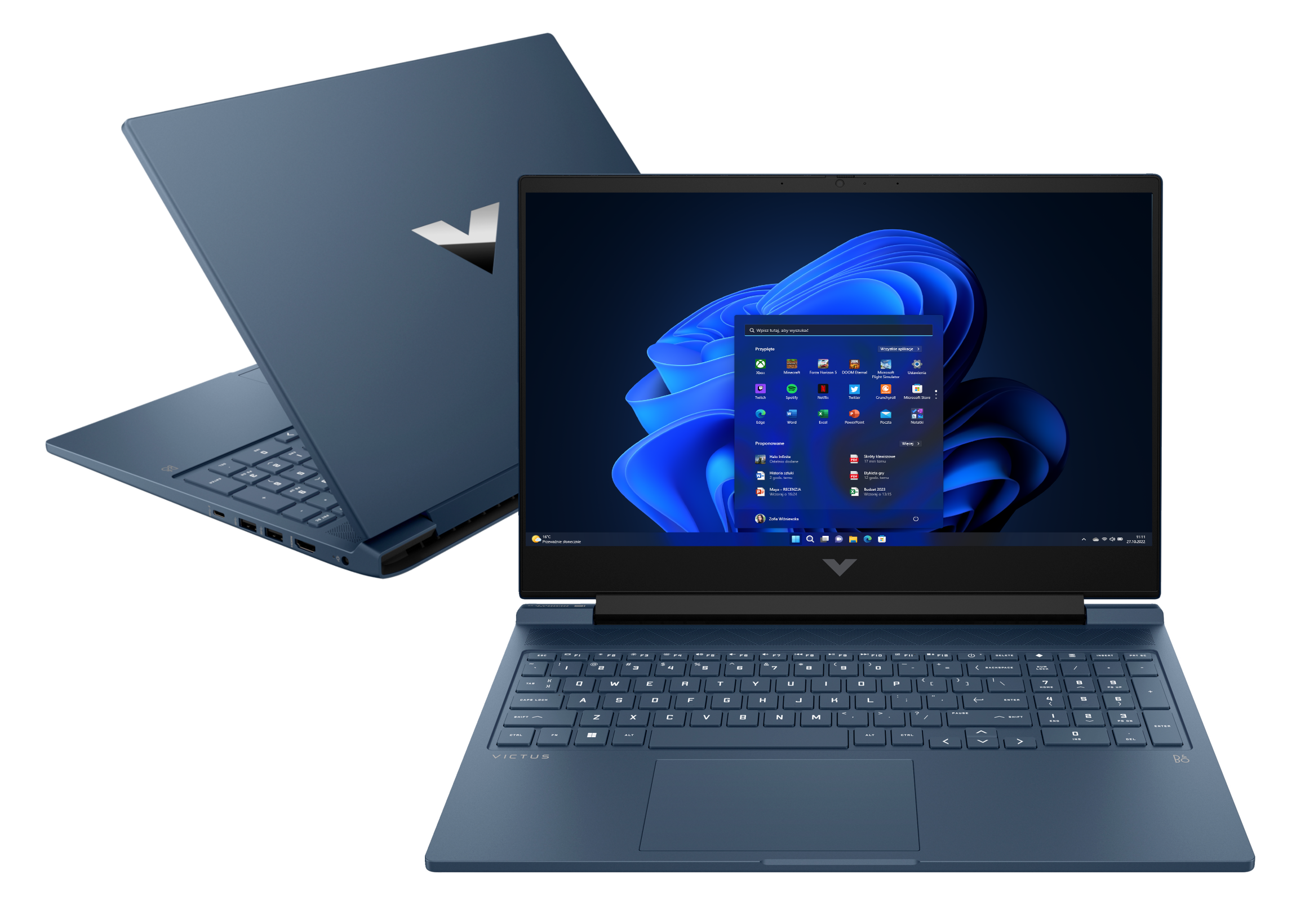 Niebieski laptop, otwarty, z pulpitem Windows. Drugi laptop w tle, zamknięty.