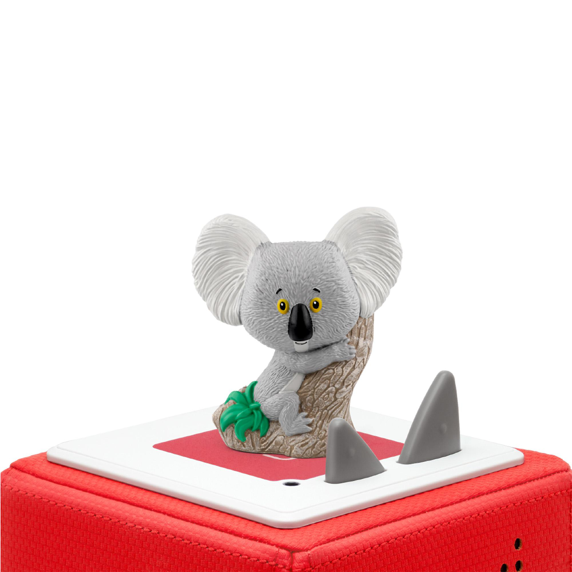 Ein Spielzeugkoala sitzt auf einem Ast. Es befindet sich auf einem roten Würfel mit zwei grauen Flossenformen.