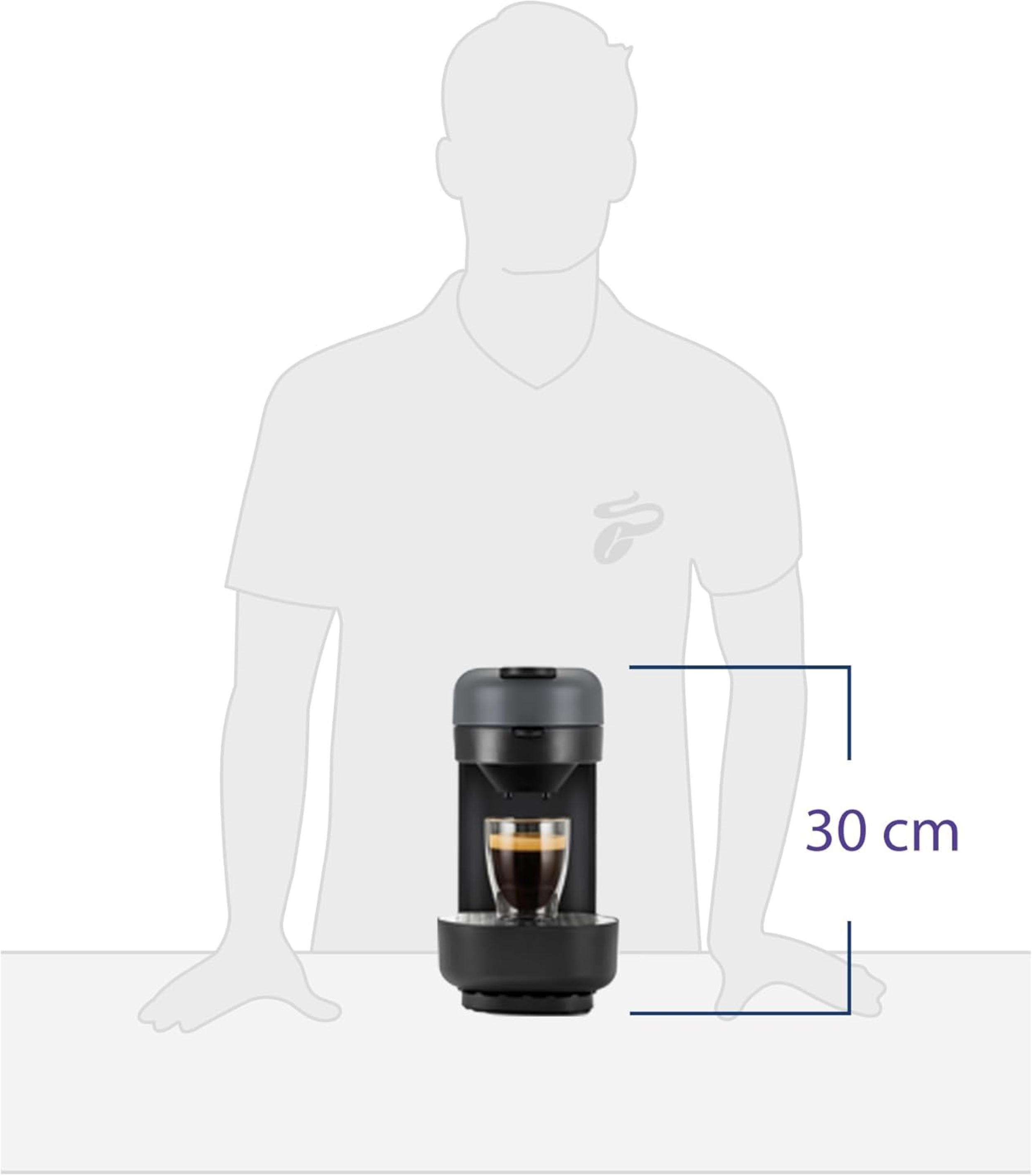 Eine Kaffeemaschine mit einem Glas Kaffee. Eine Person steht dahinter.