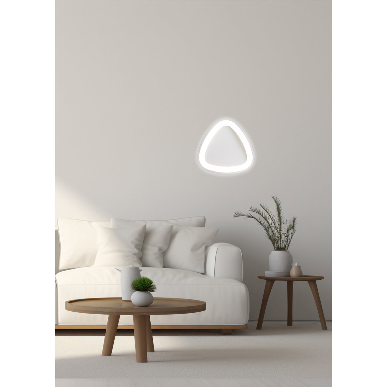 Divano bianco e tavolino con pianta. Lampada da parete triangolare accesa.
