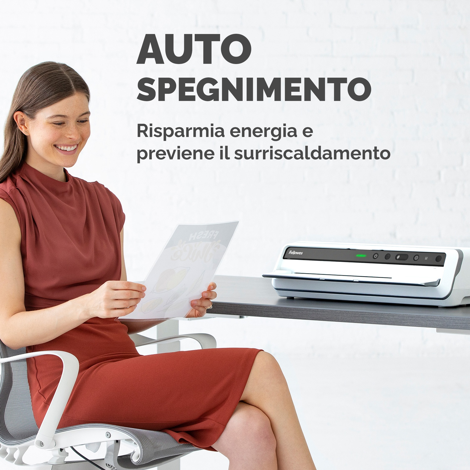 Una donna seduta a una scrivania sorridente. Una plastificatrice sulla scrivania. Testo in italiano sullo spegnimento automatico.