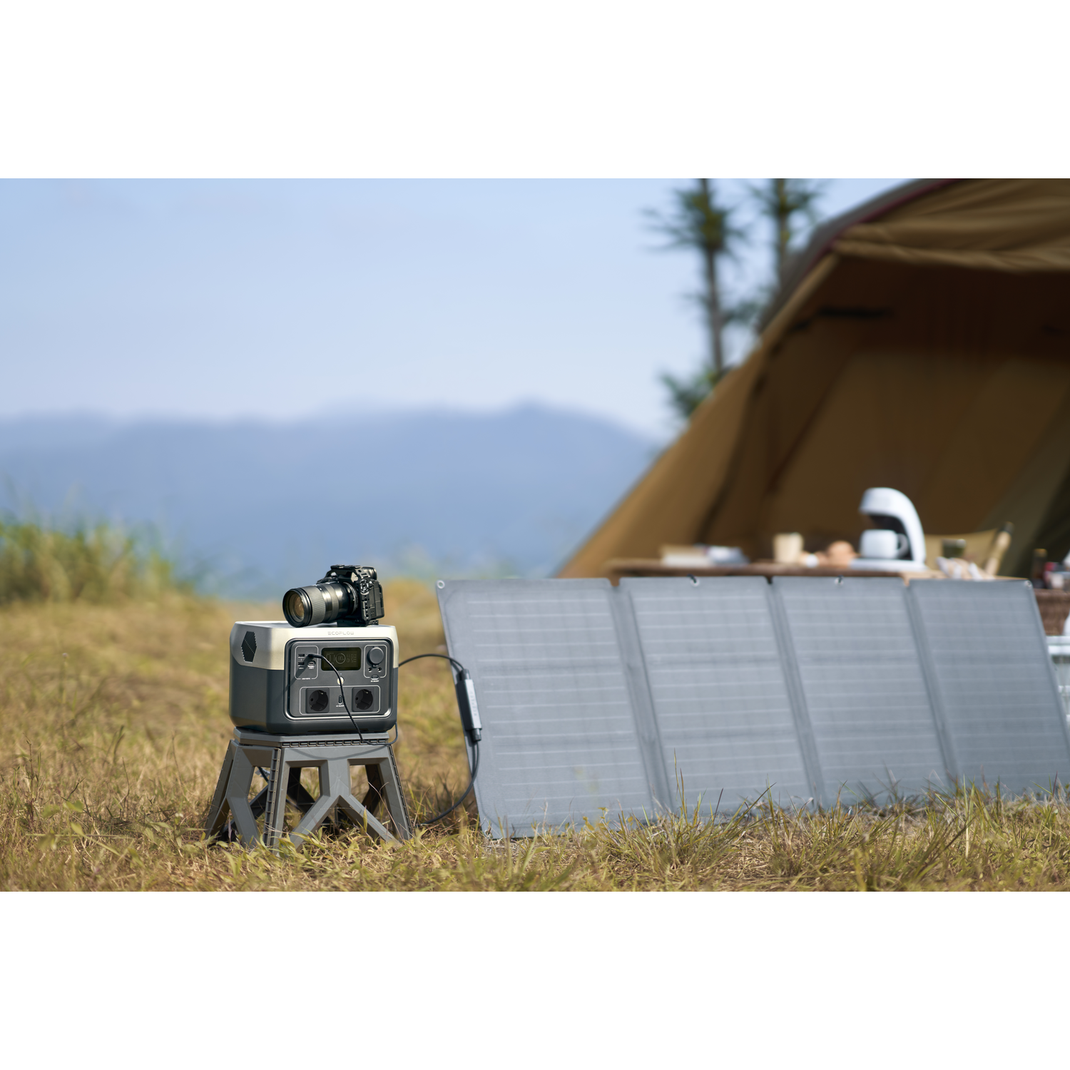 A camera and a power station on a folding stool in a camping setting with solar panels.