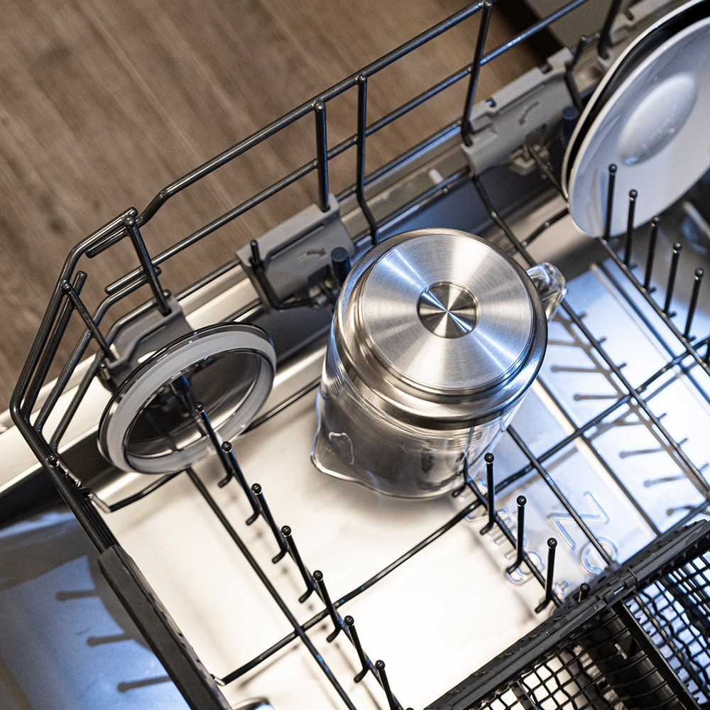 Ein klarer Wasserkrug und Deckel in der Spülmaschine.