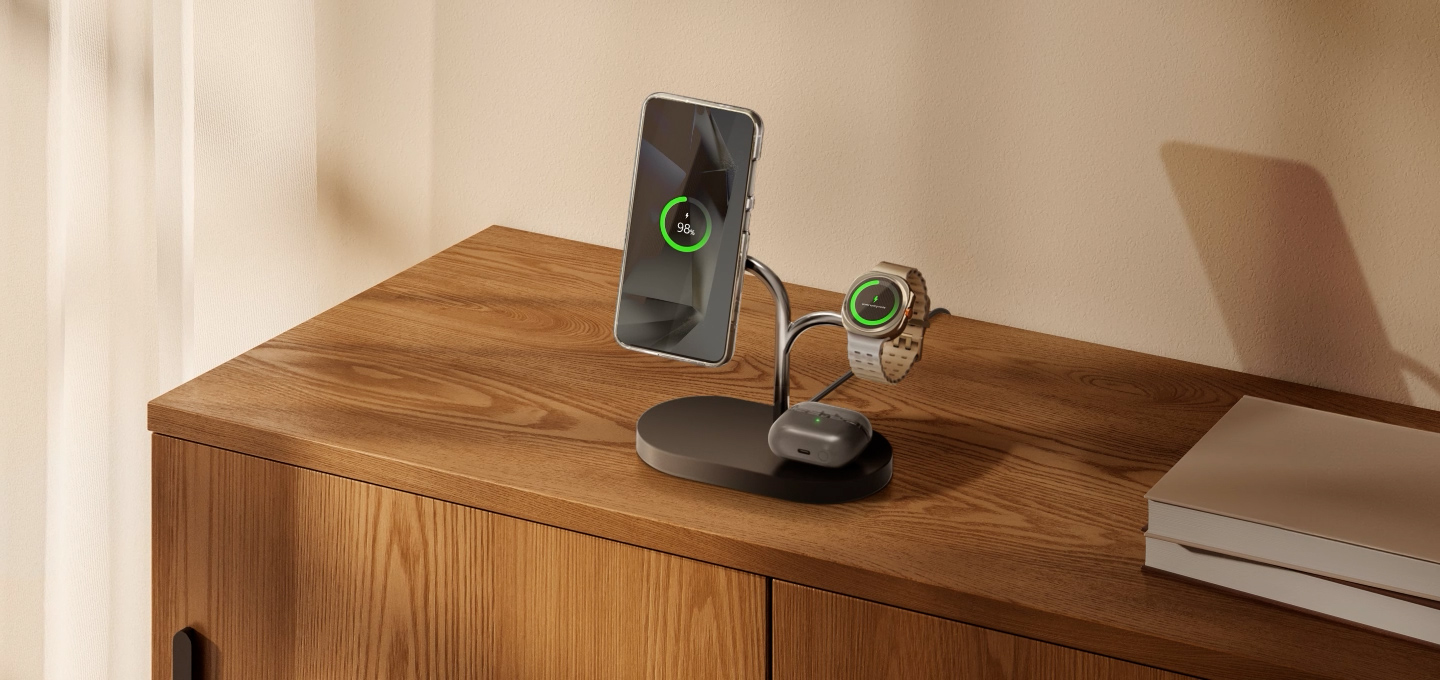 Stazione di ricarica con telefono, orologio e auricolari su superficie in legno.
