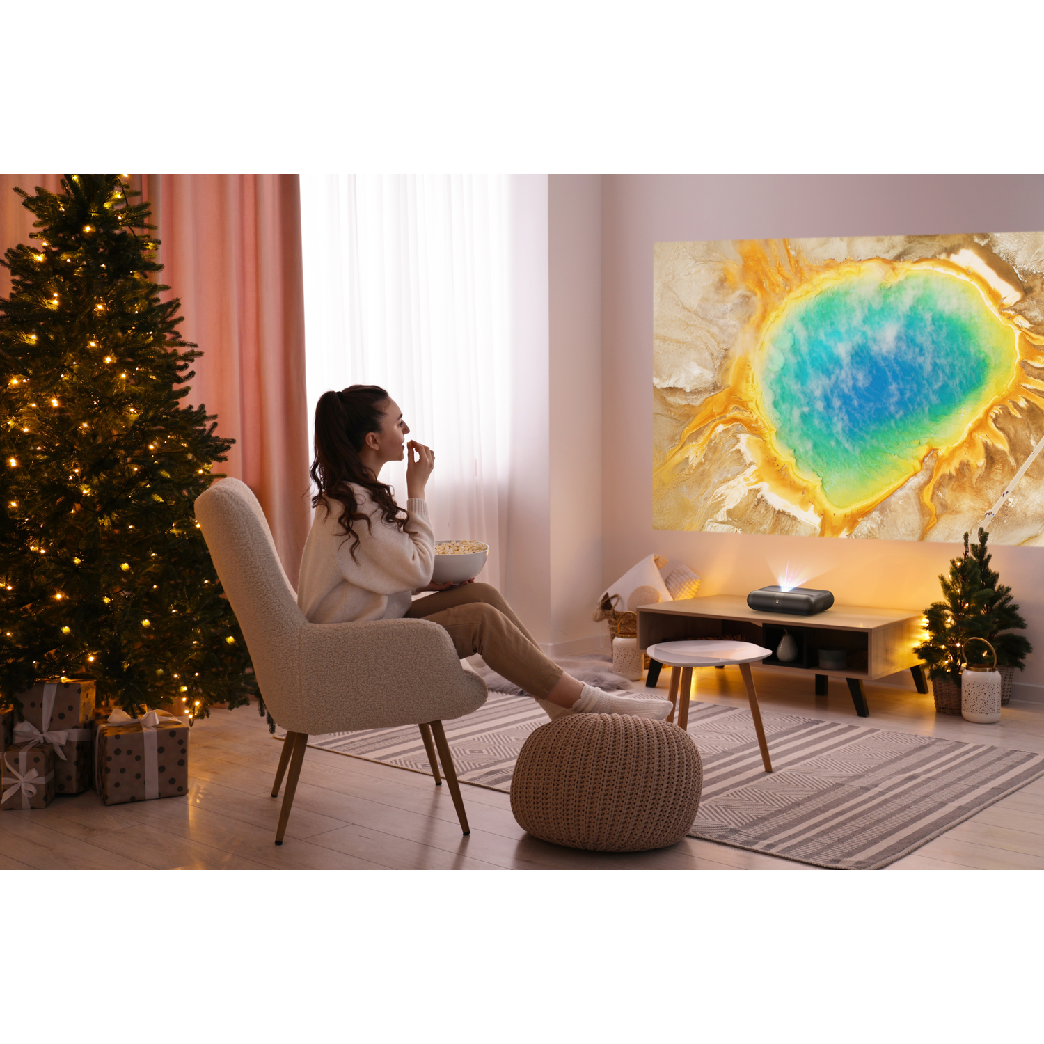 Vrouw die een geprojecteerde afbeelding op een muur bekijkt. Kerstboom en decoraties in de kamer.