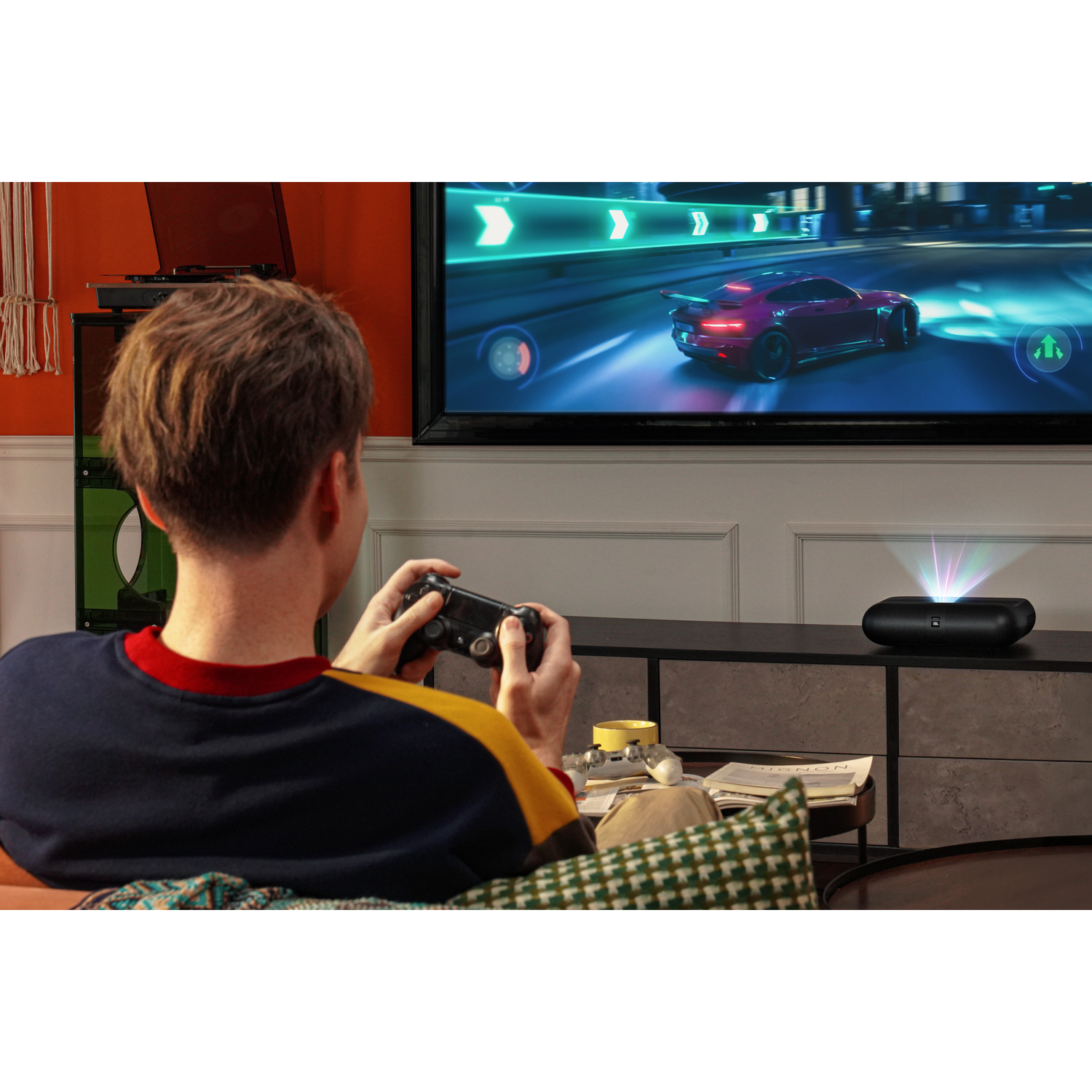 Man speelt een spel op tv. Een projector staat voor de tv en projecteert het spel.