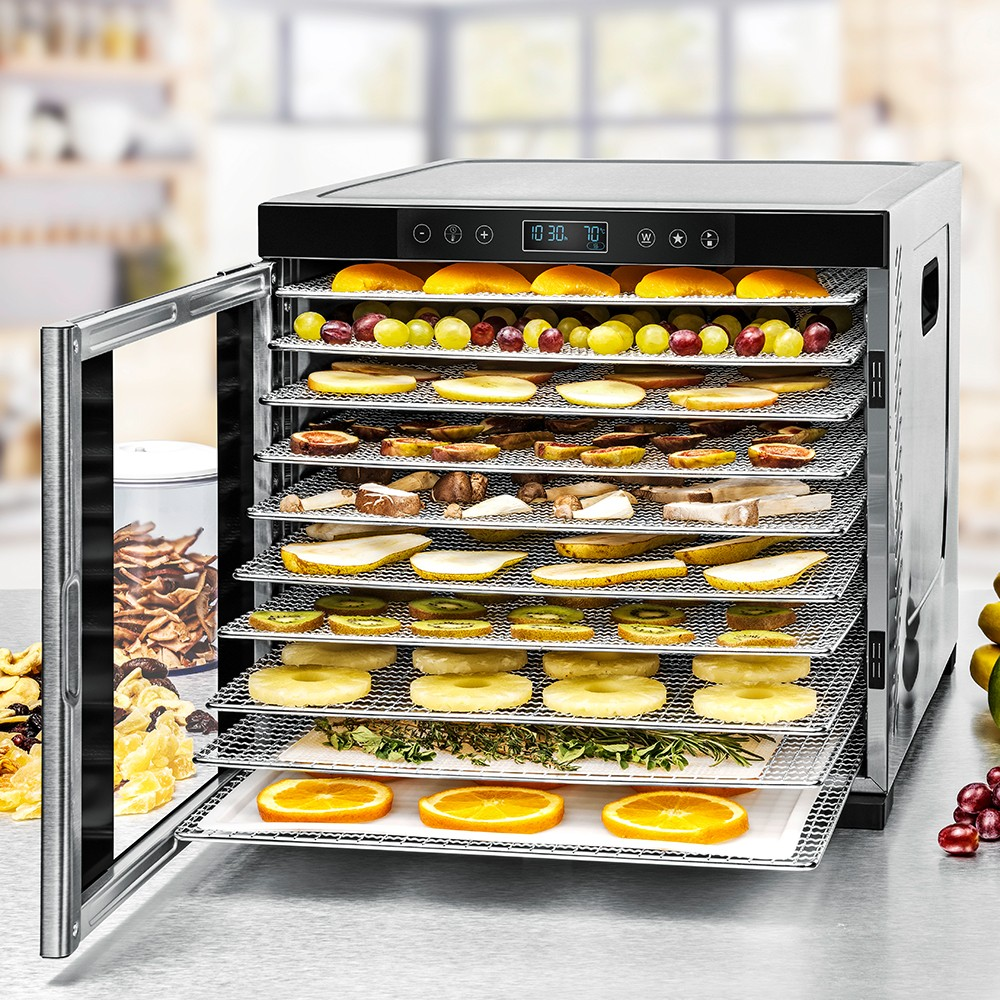 Lebensmittel-Dehydrator mit offener Tür, die verschiedene Früchte und Gemüse auf Tabletts zeigt.