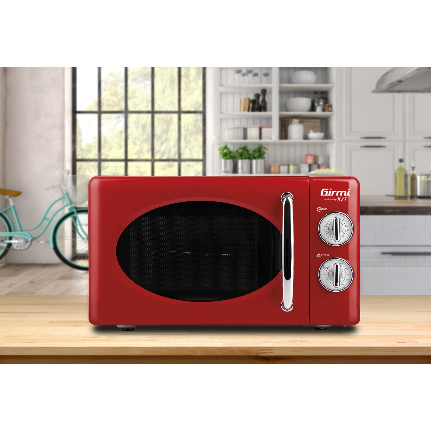 Microonde rosso su bancone di legno. Due manopole, finestra ovale. Sfondo: cucina.
