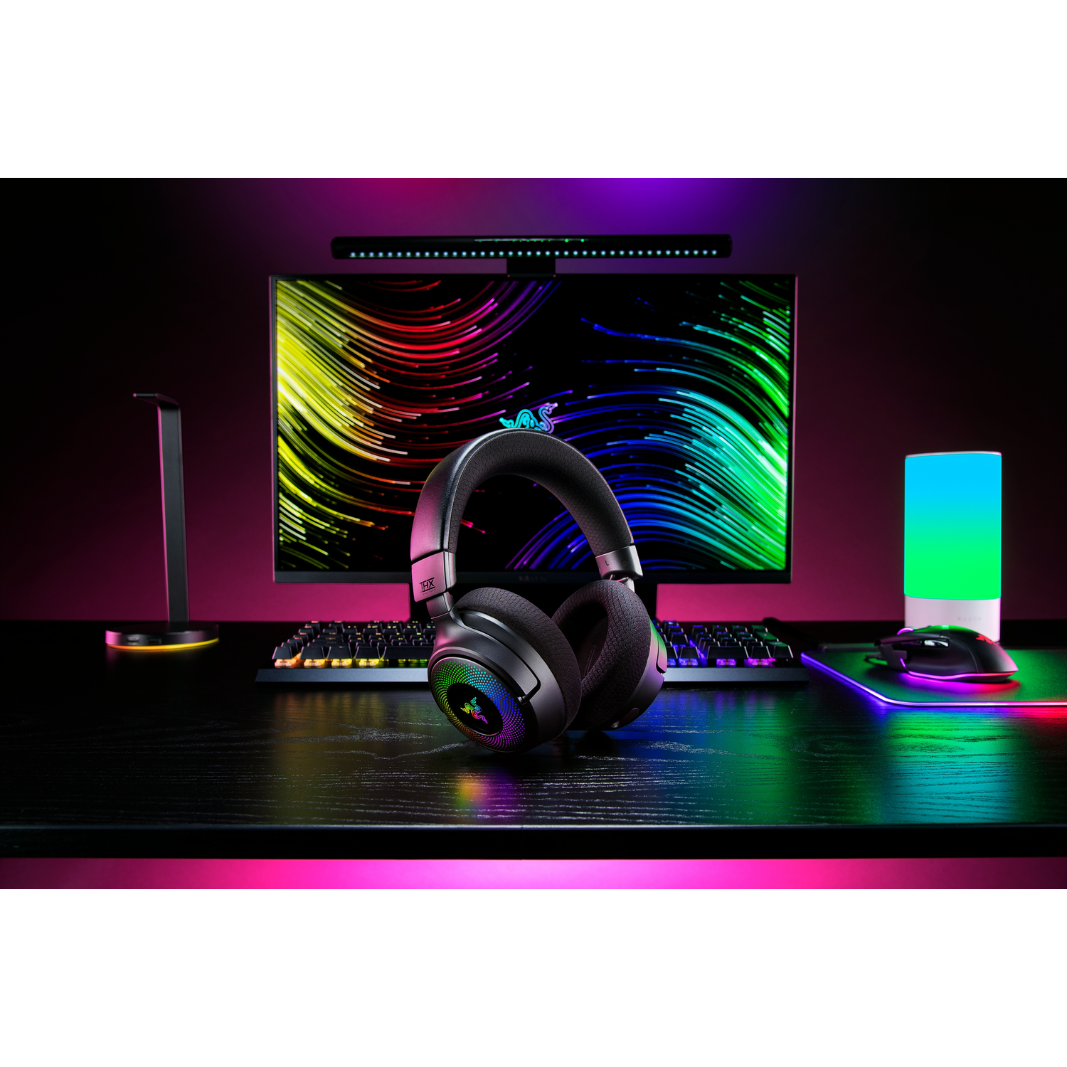 Gaming-opstelling met koptelefoon, monitor, toetsenbord en muis op een bureau. Omgevingslicht.