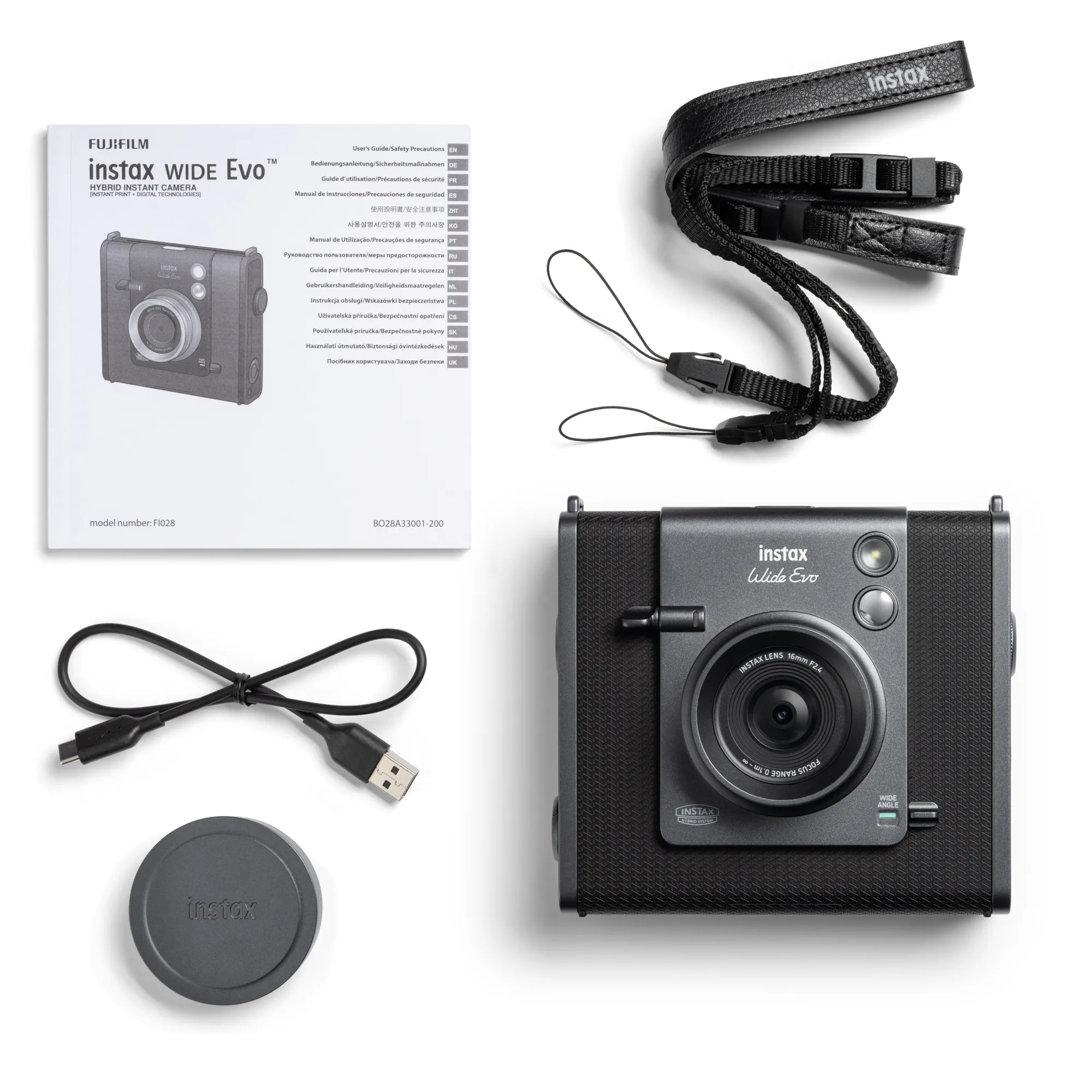 Fotocamera istantanea, manuale di istruzioni, cinturino, cavo USB e copriobiettivo su superficie bianca.