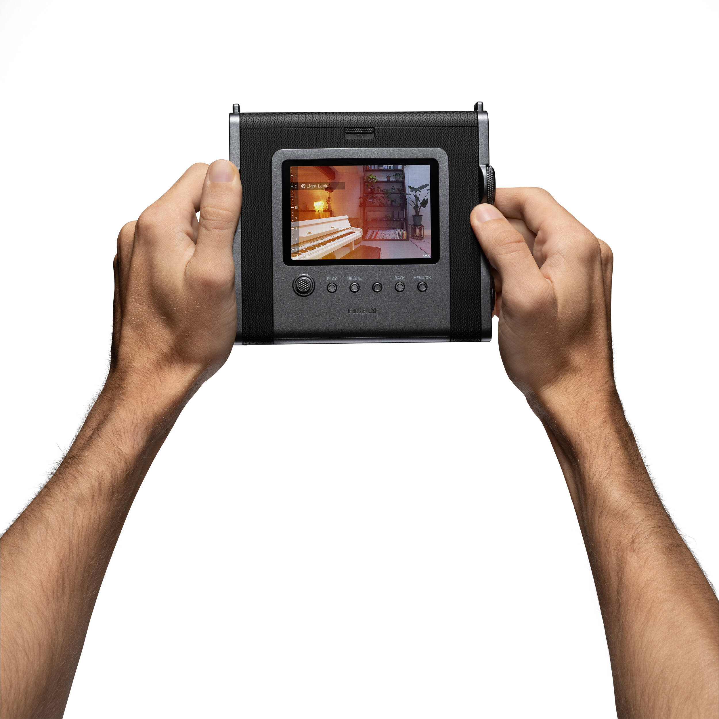 Mani che tengono una fotocamera istantanea nera con schermo.