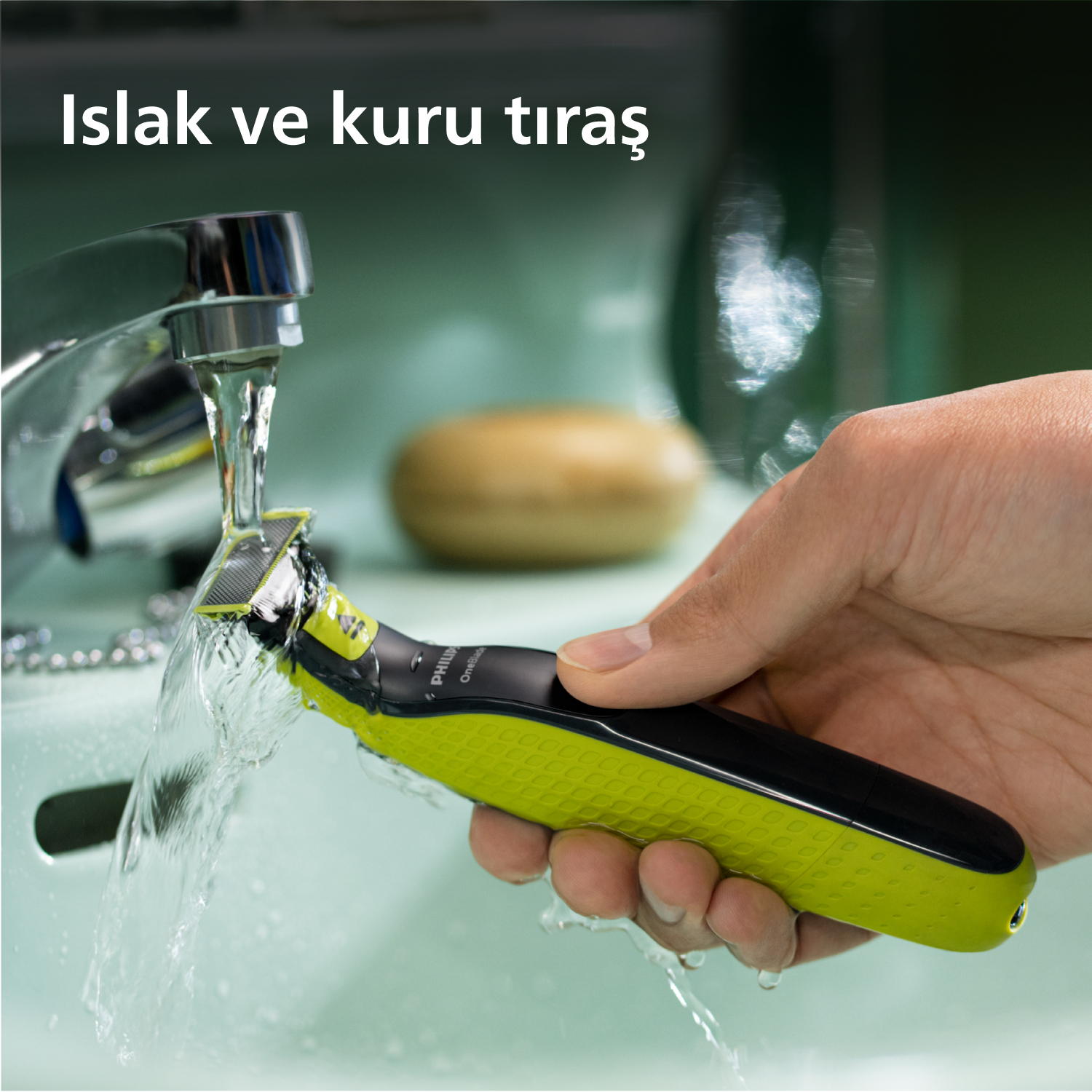 Bir kişi tıraş oluyor. Yeşil ve siyah bir Philips OneBlade tıraş makinesinin üzerinden bir su akışı geçiyor.