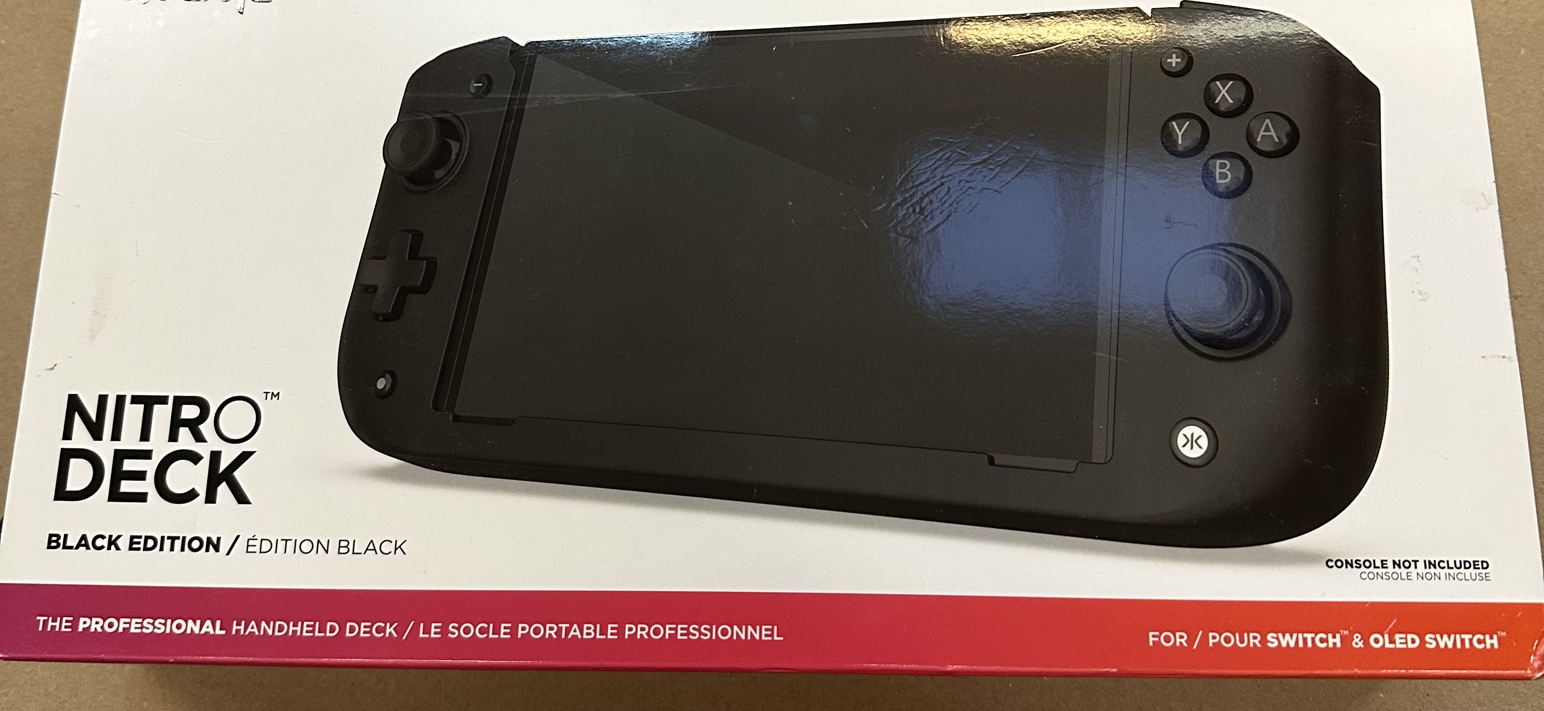 Czarna konsola do gier Nitro Deck na białym i czerwonym pudełku, urządzenie przenośne jest na środku.